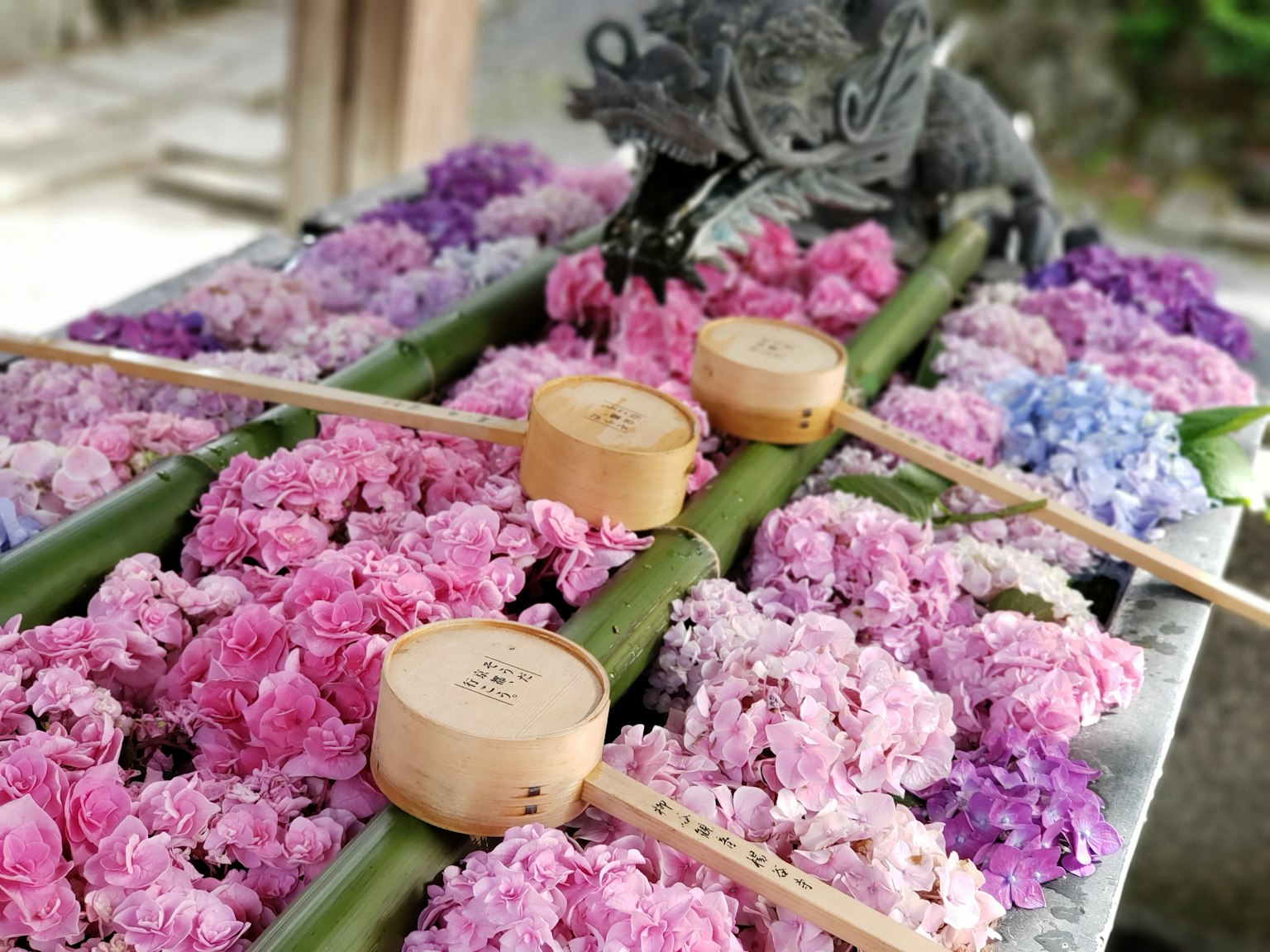 A floral altar adorned with pink and purple flowers featuring bamboo water basins