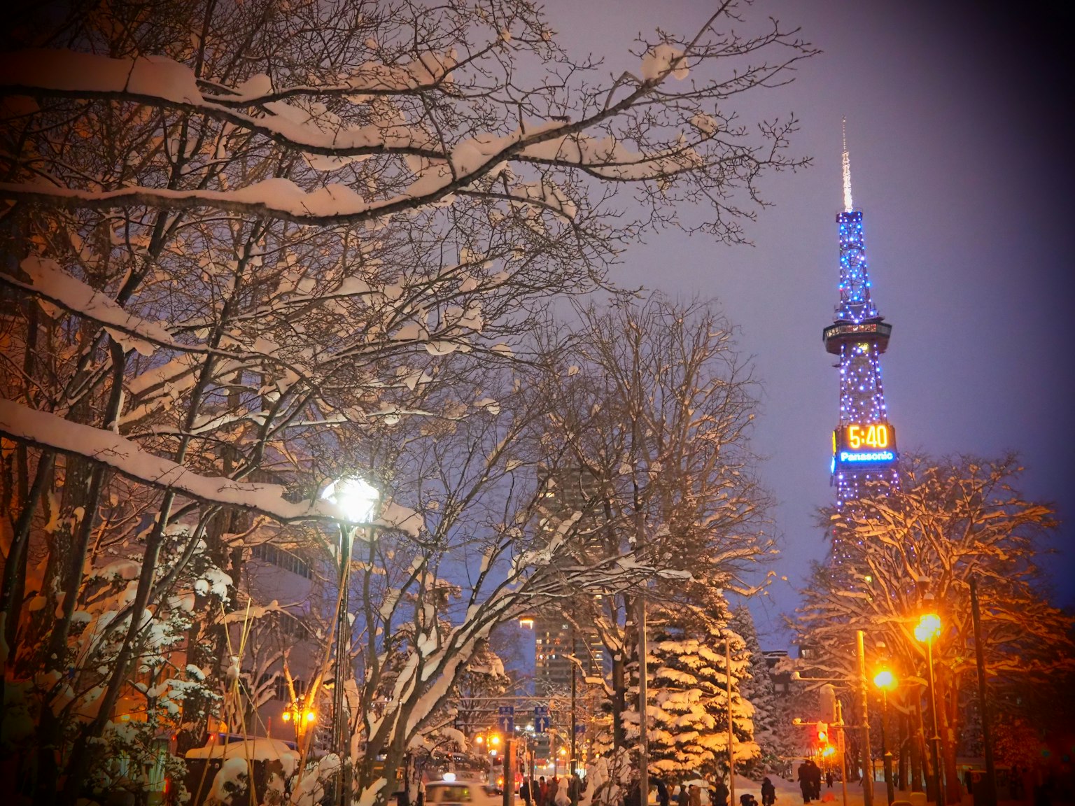 Winterszene mit schneebedeckten Bäumen und einem blau beleuchteten Turm