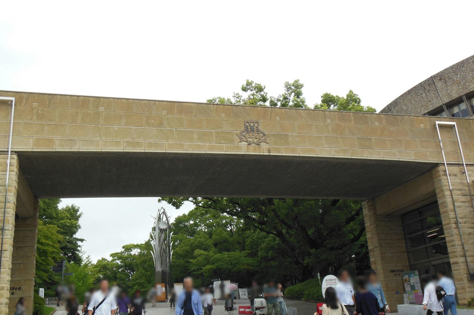 熙熙攘攘的拱门场景，人们在下面走过，周围是郁郁葱葱的绿树