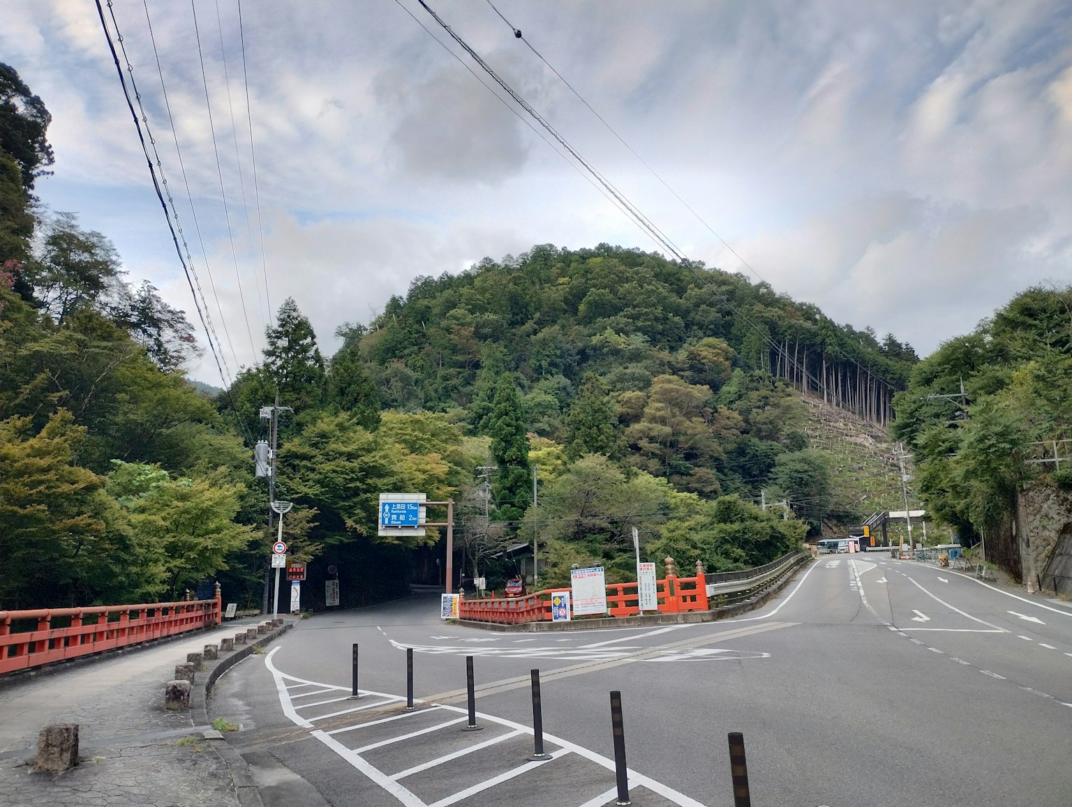 Scenic view of a green mountain and intersecting road with a red bridge and signage