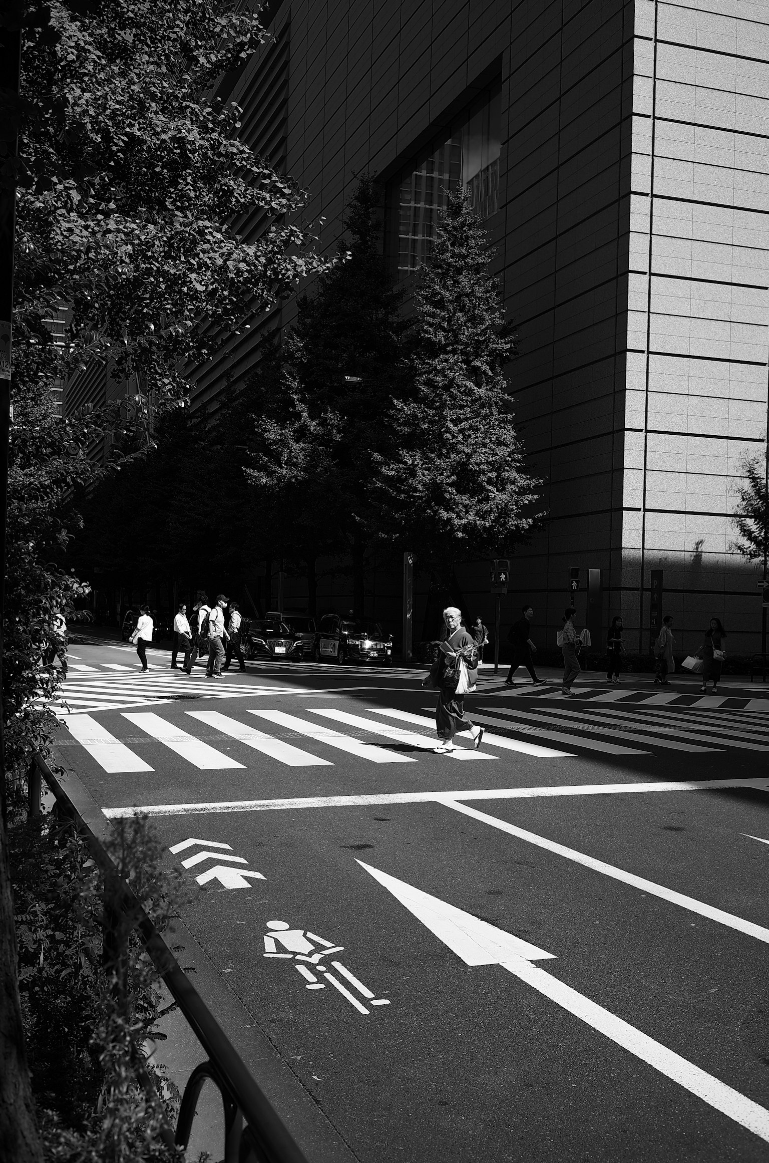 Pedestrians crossing a black and white striped crosswalk with skyscrapers in the background