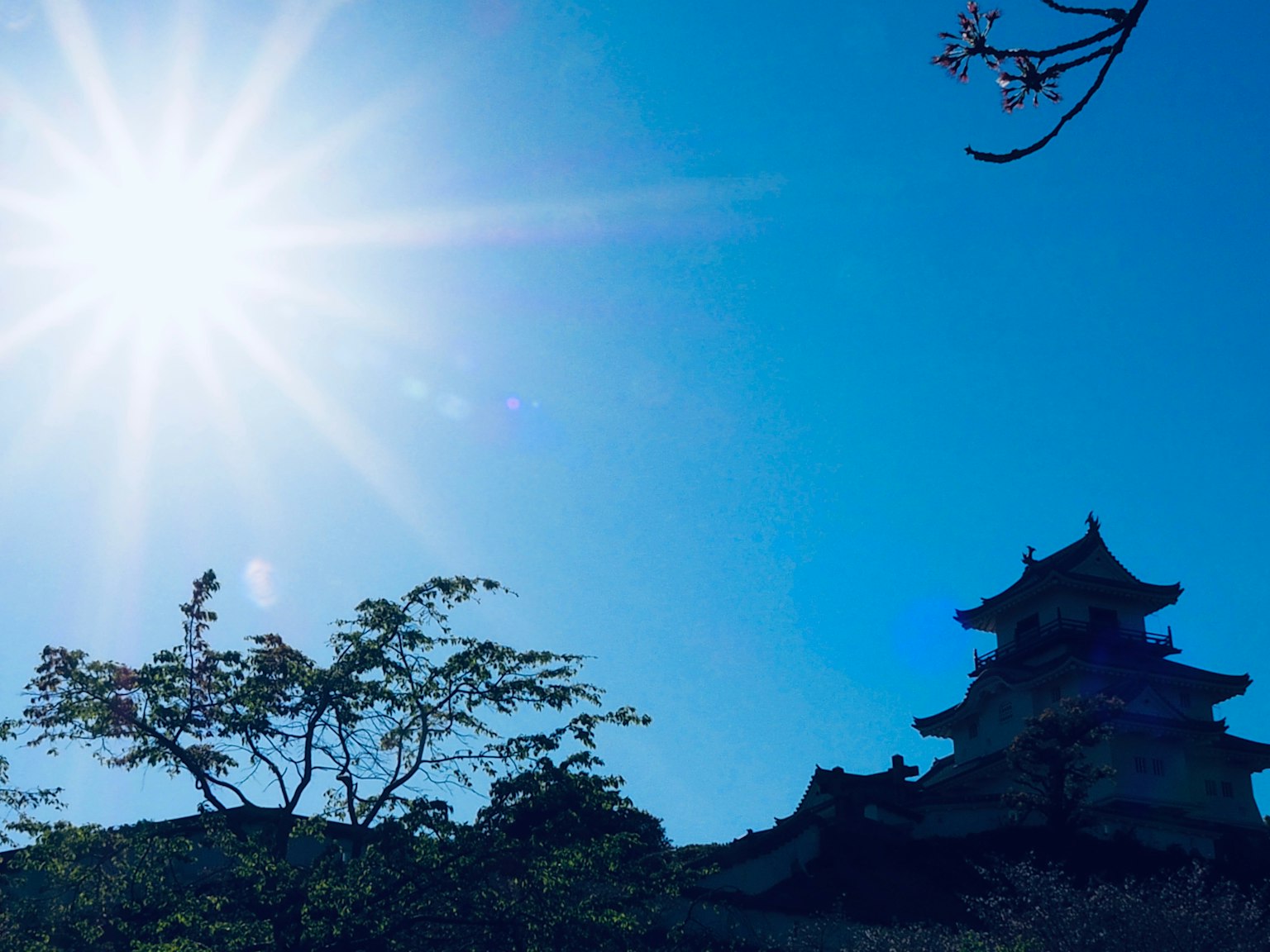Castle silhouette against a bright blue sky and shining sun