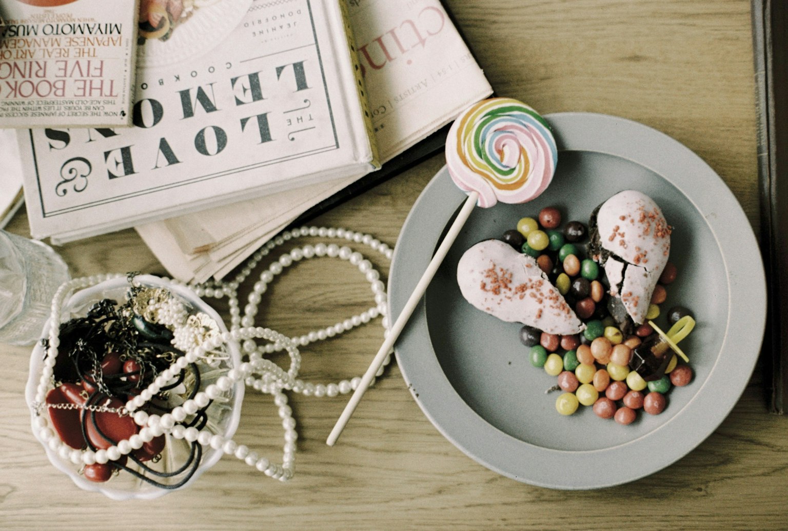 Bunte Bonbons und Eis auf einem Teller mit Zeitschriften im Hintergrund