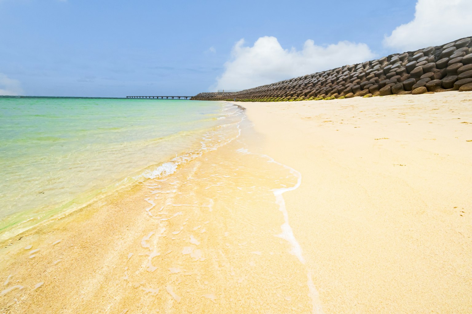 Malersicher Strand mit goldenem Sand und türkisfarbenem Wasser unter klarem blauen Himmel