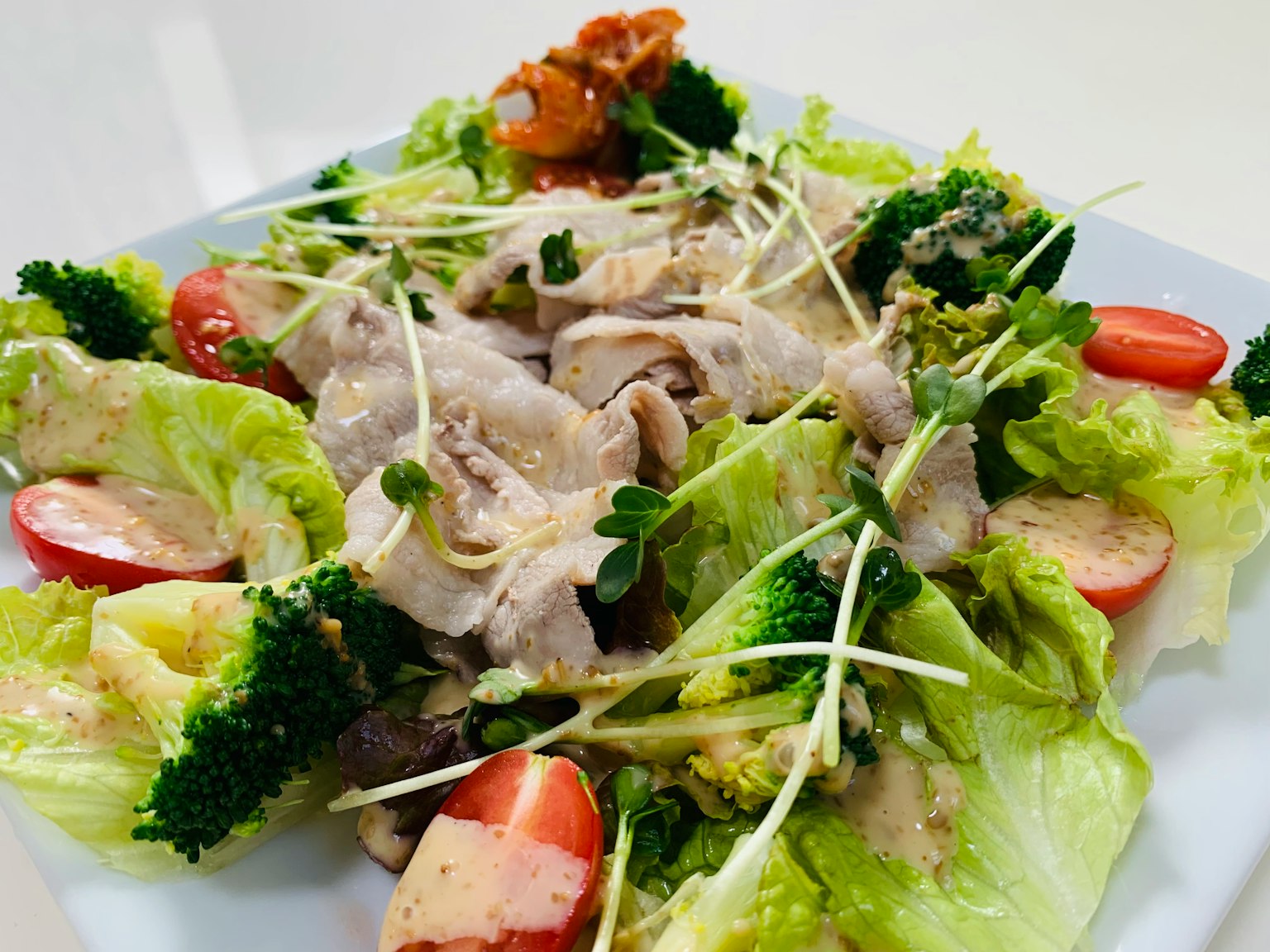 Une salade fraîche garnie de poulet, de brocoli et de tomates sur une assiette blanche