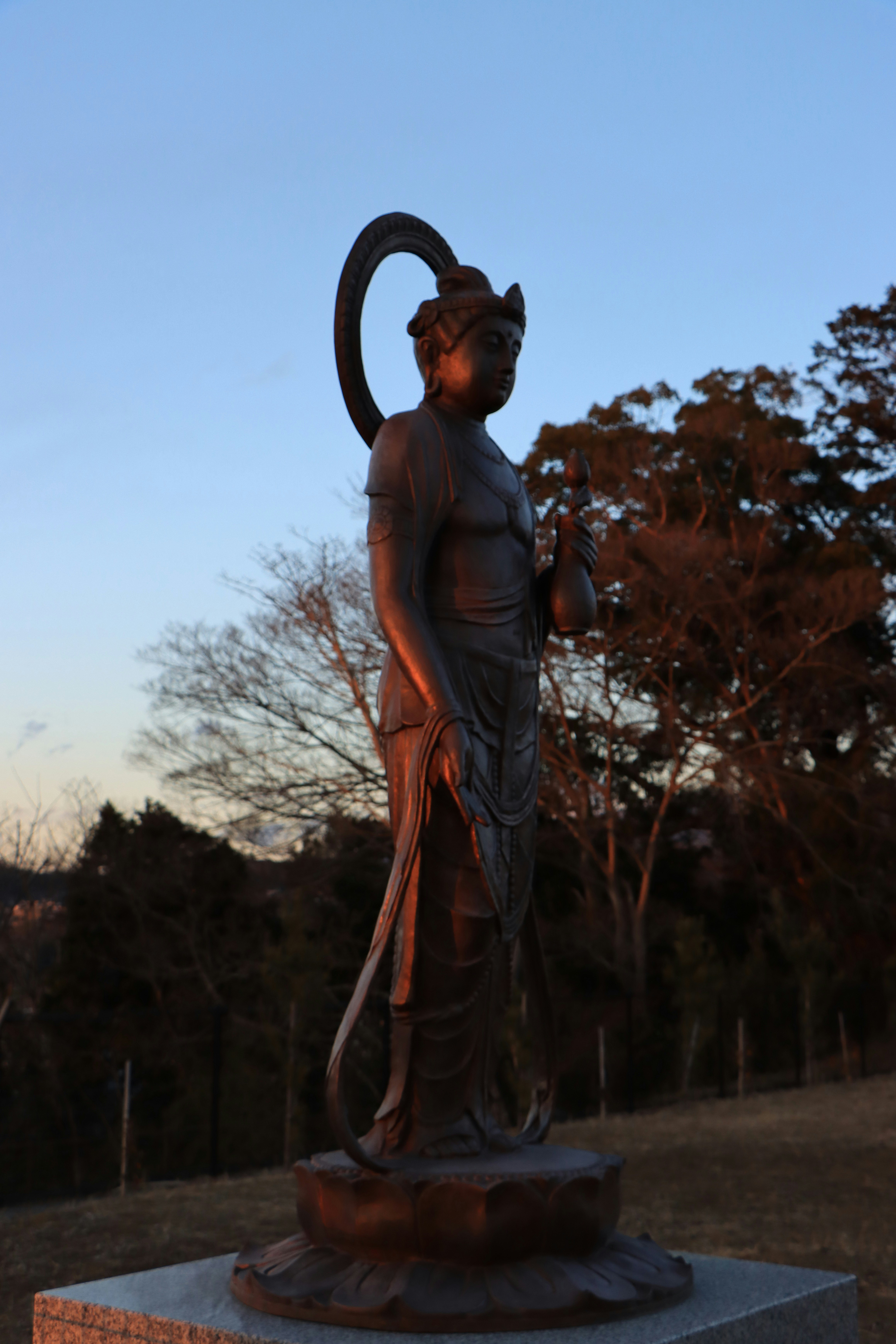 夕暮れの森の小道に立つ仏像
