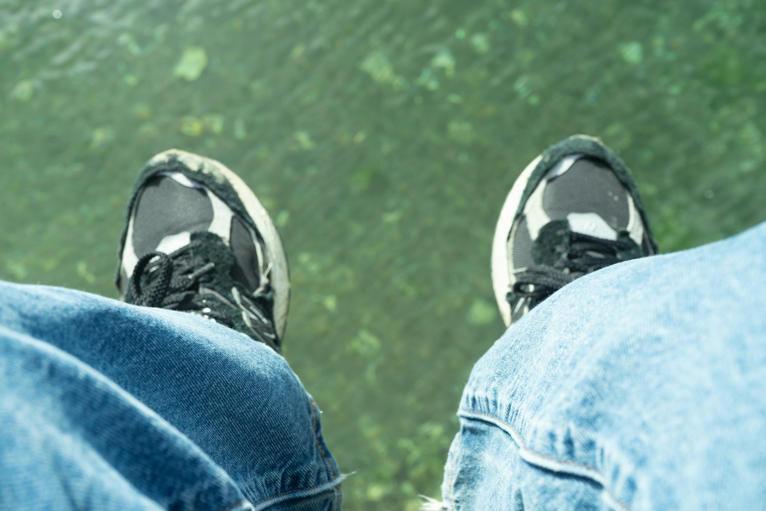 Photo de pieds au-dessus d'une surface d'eau verte