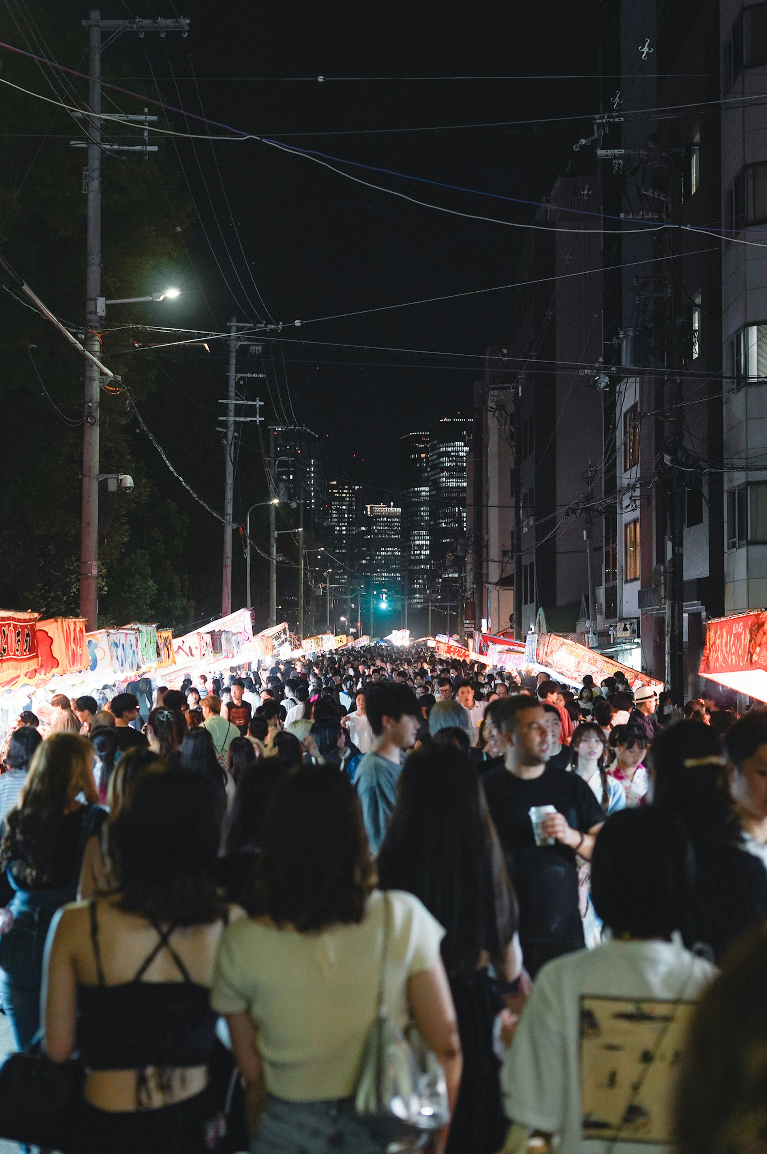 夜の街路に並ぶ提灯と人混みの宵祭りの風景