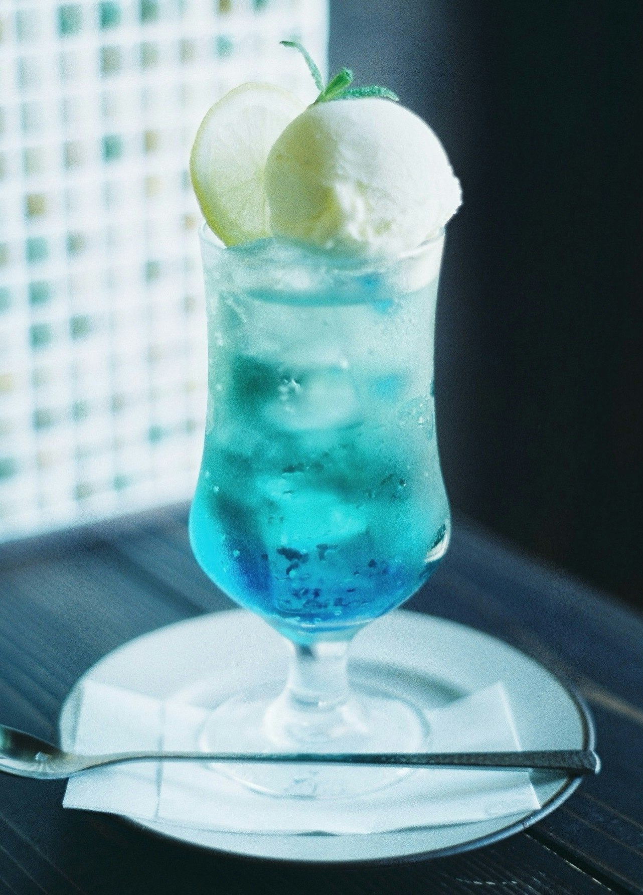 青いソーダドリンクのグラスと氷のクローズアップ