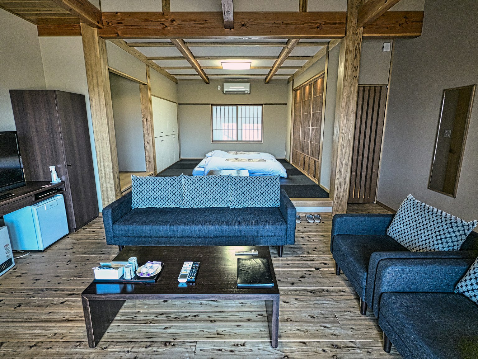 Modern Japanese room interior with wooden beams and flooring featuring sofas and a coffee table