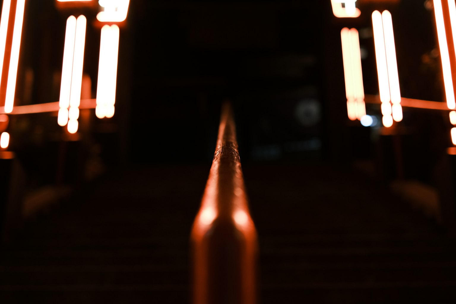 Una escena nocturna borrosa con un pasamanos de escalera y luces de neón circundantes