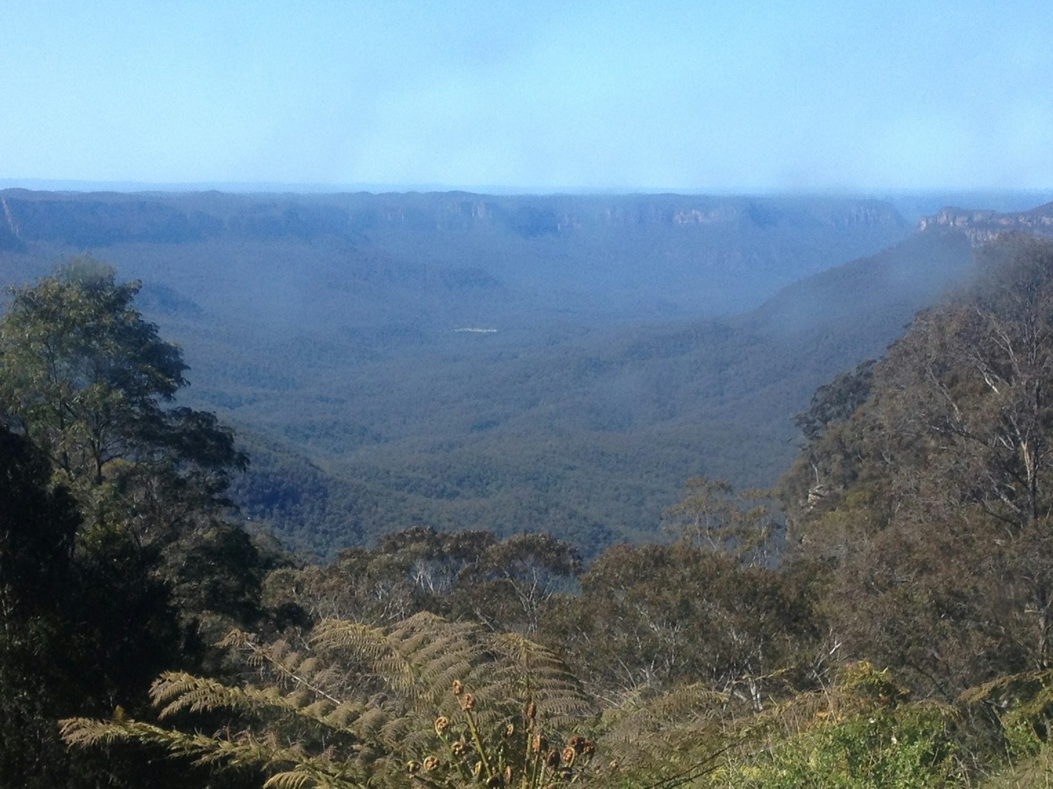 Amplio paisaje de valle montañosa con cielo azul y niebla