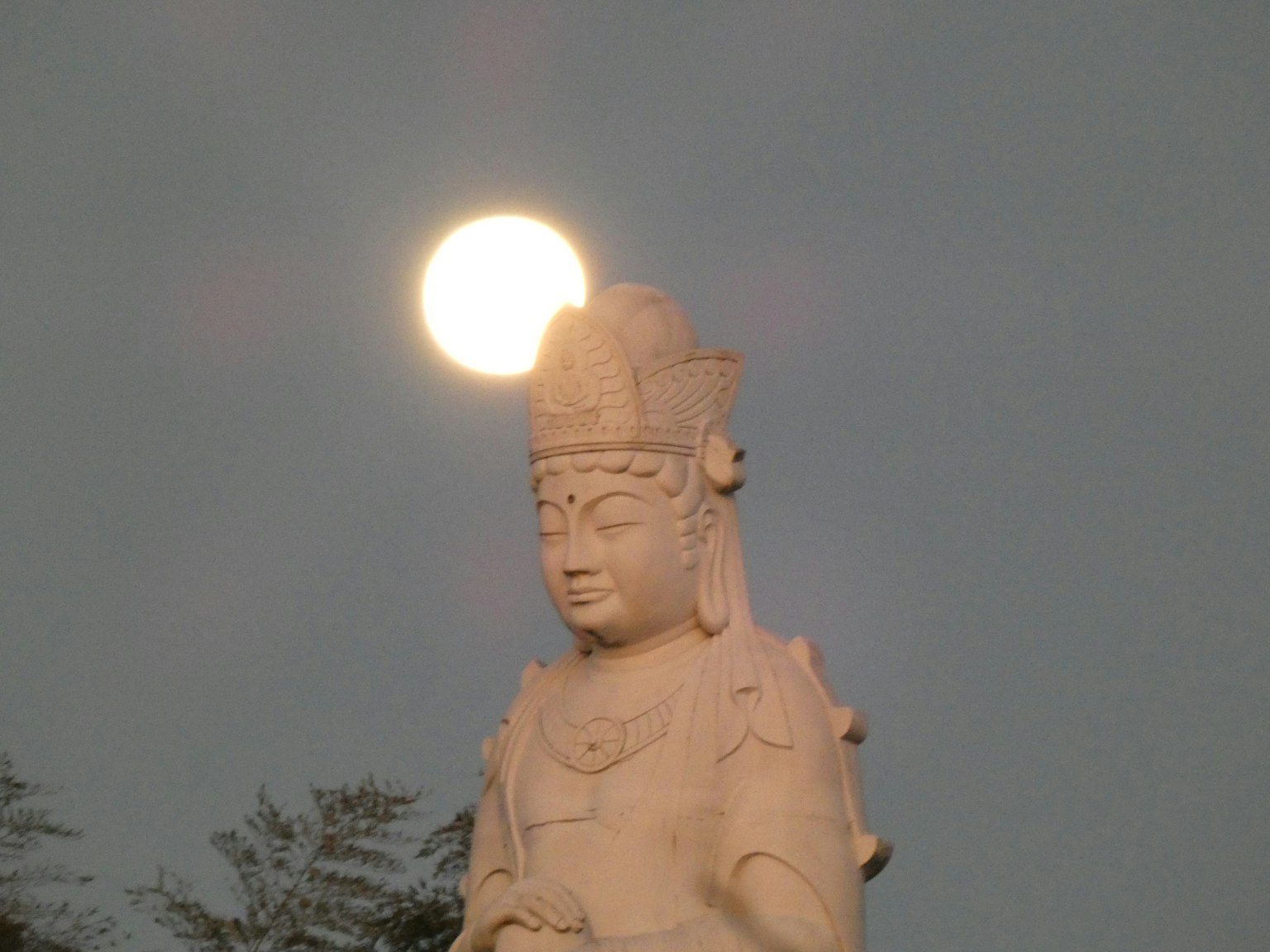 Statua di Kannon con la luna che sorge dietro