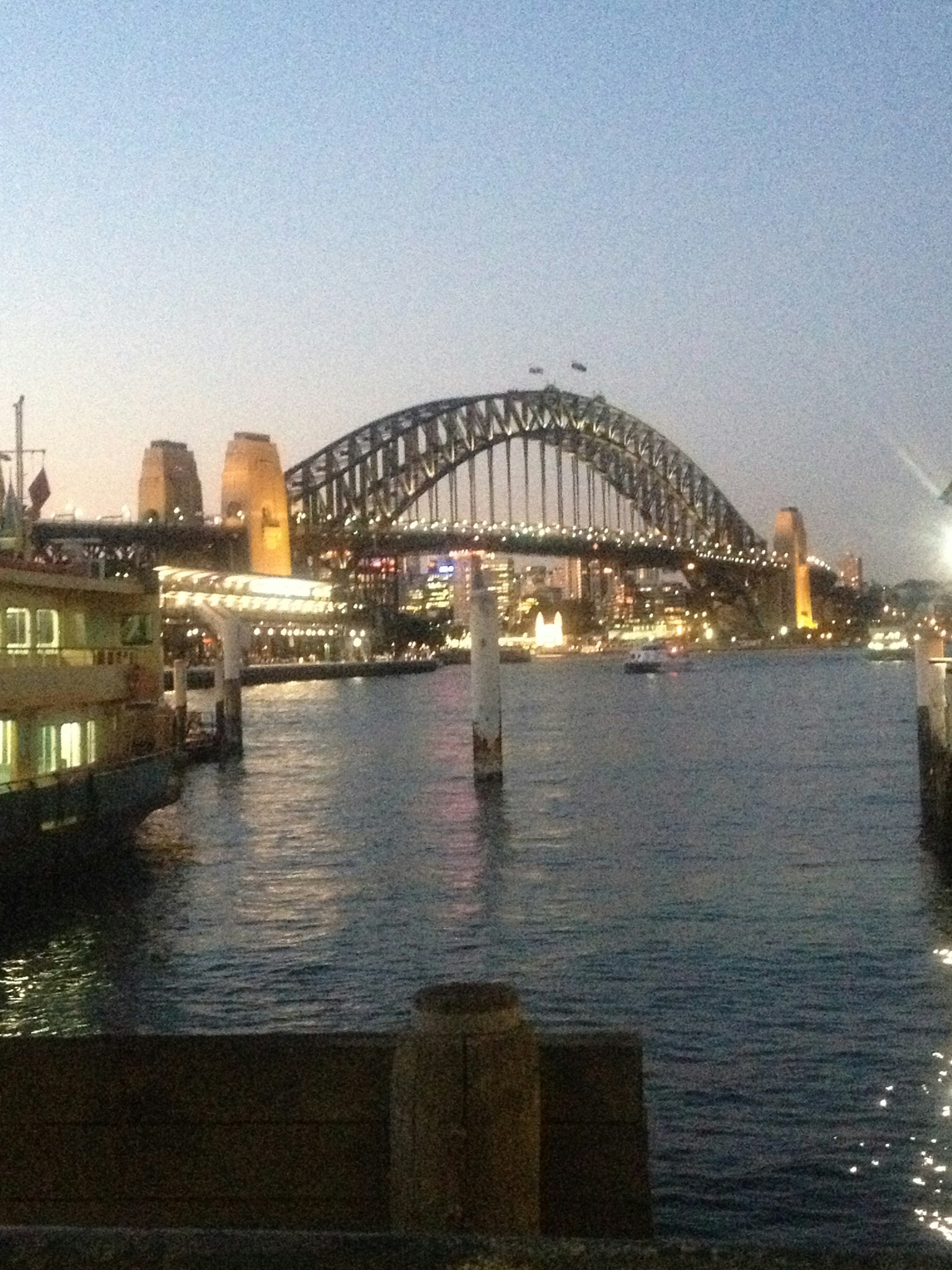 Sydney Harbour Bridge illuminated at dusk over the water