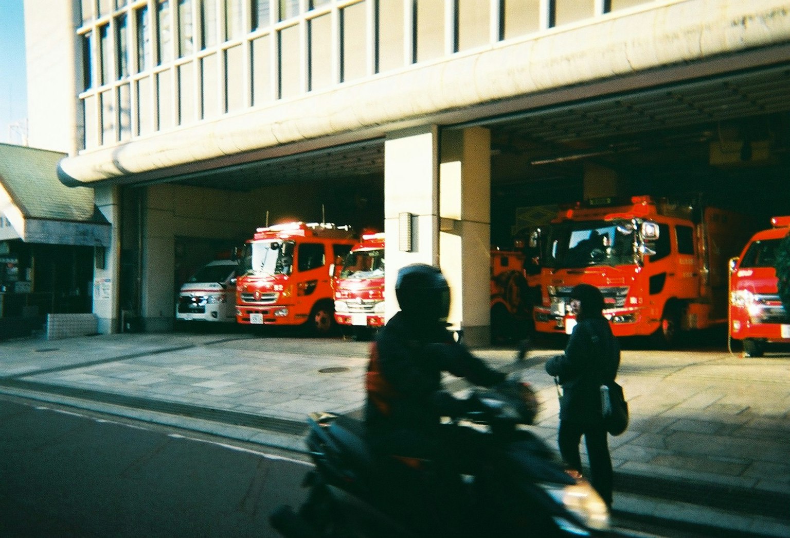 Extérieur de la caserne de pompiers avec des camions de pompiers rouges et des piétons passant