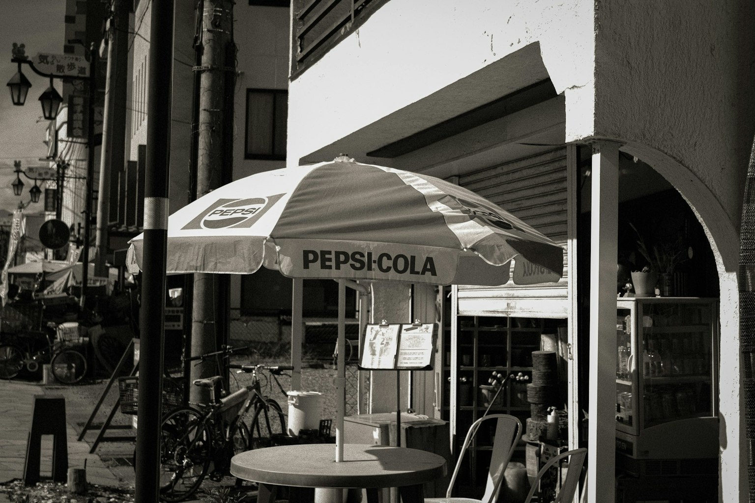 黑白场景中有一把PEPSICOLA伞和下面的桌子和椅子