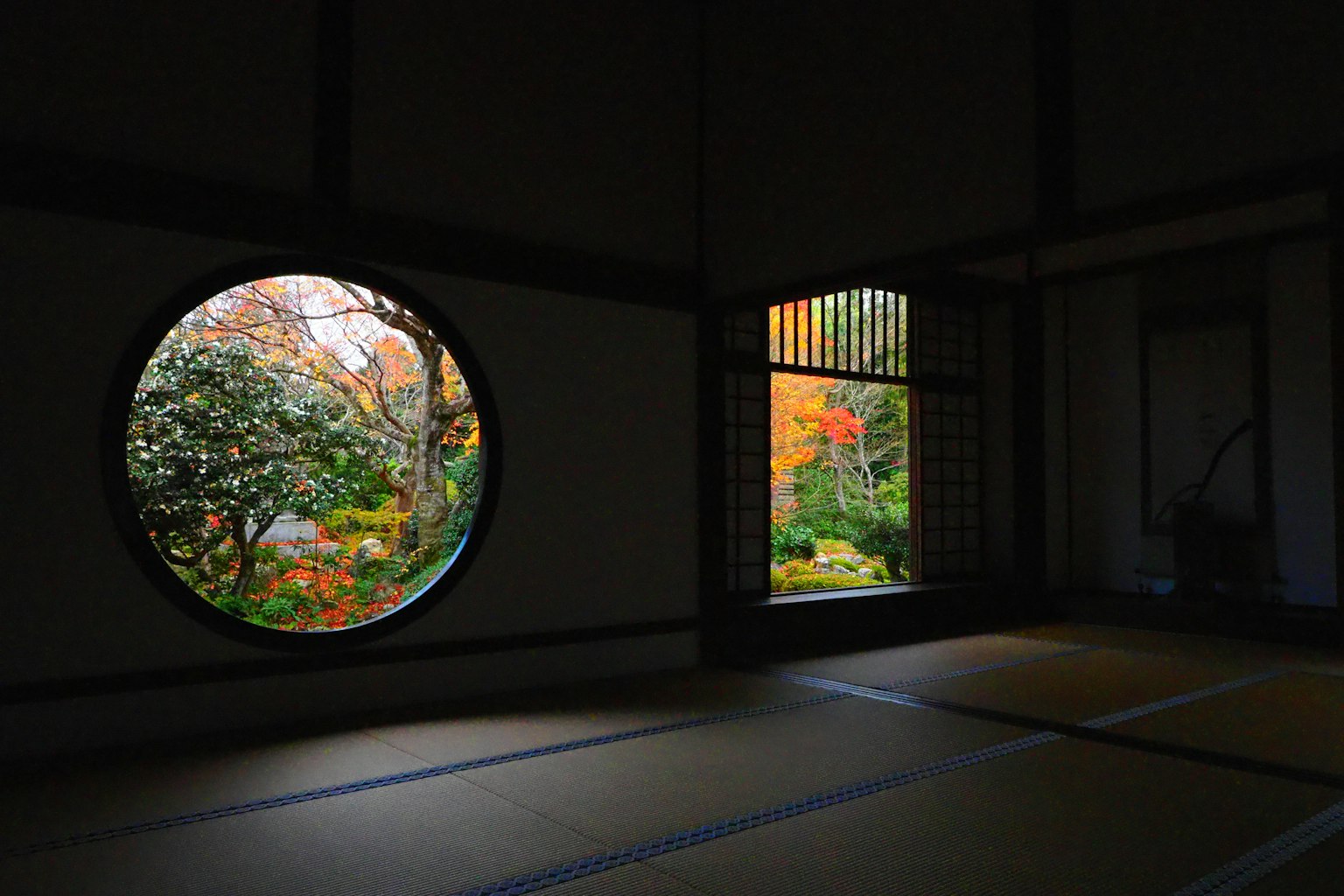 传统日本房间的内部，通过圆形和方形窗户展示秋季风景
