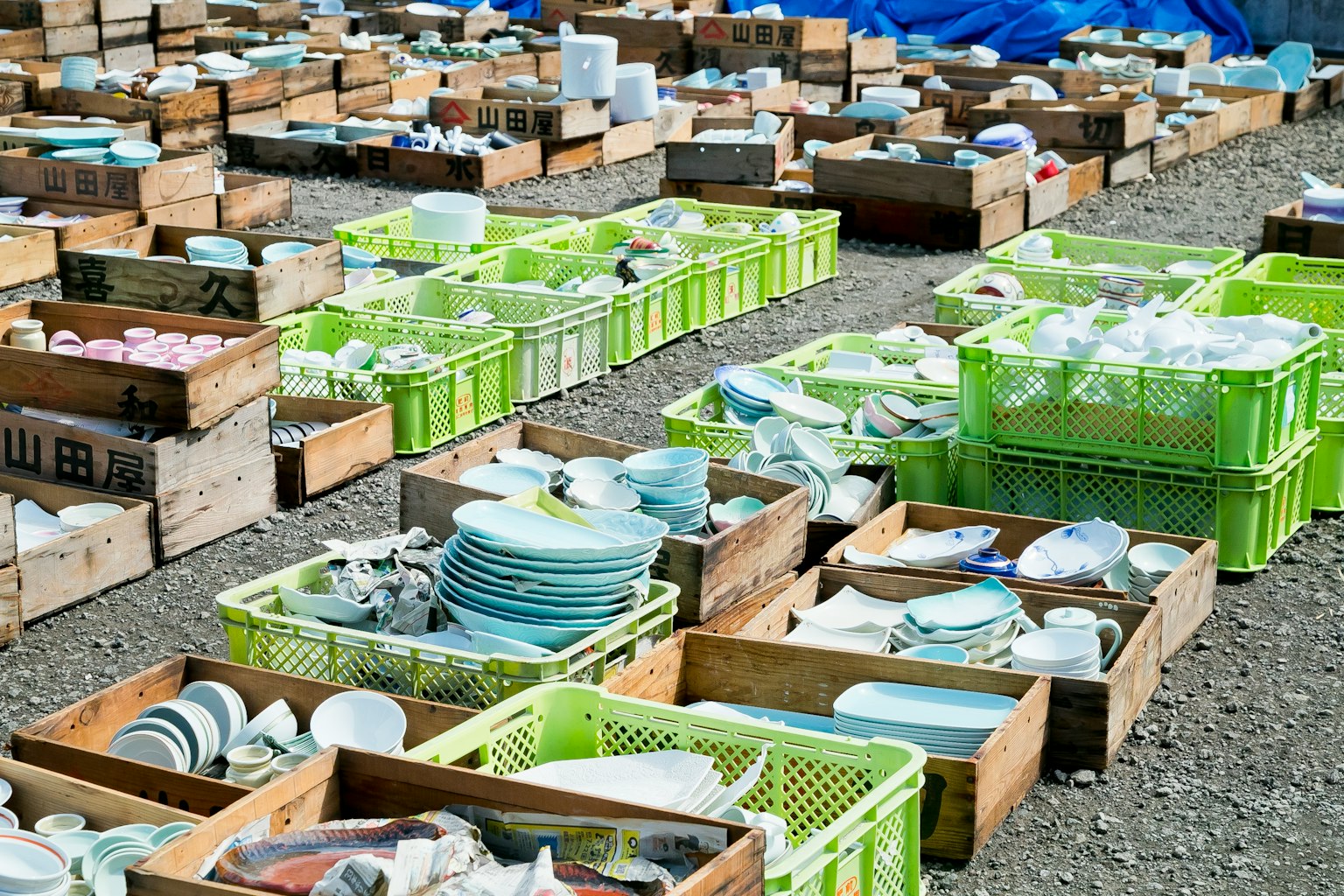 Koleksi peralatan makan yang teratur dalam kotak kayu dan keranjang hijau