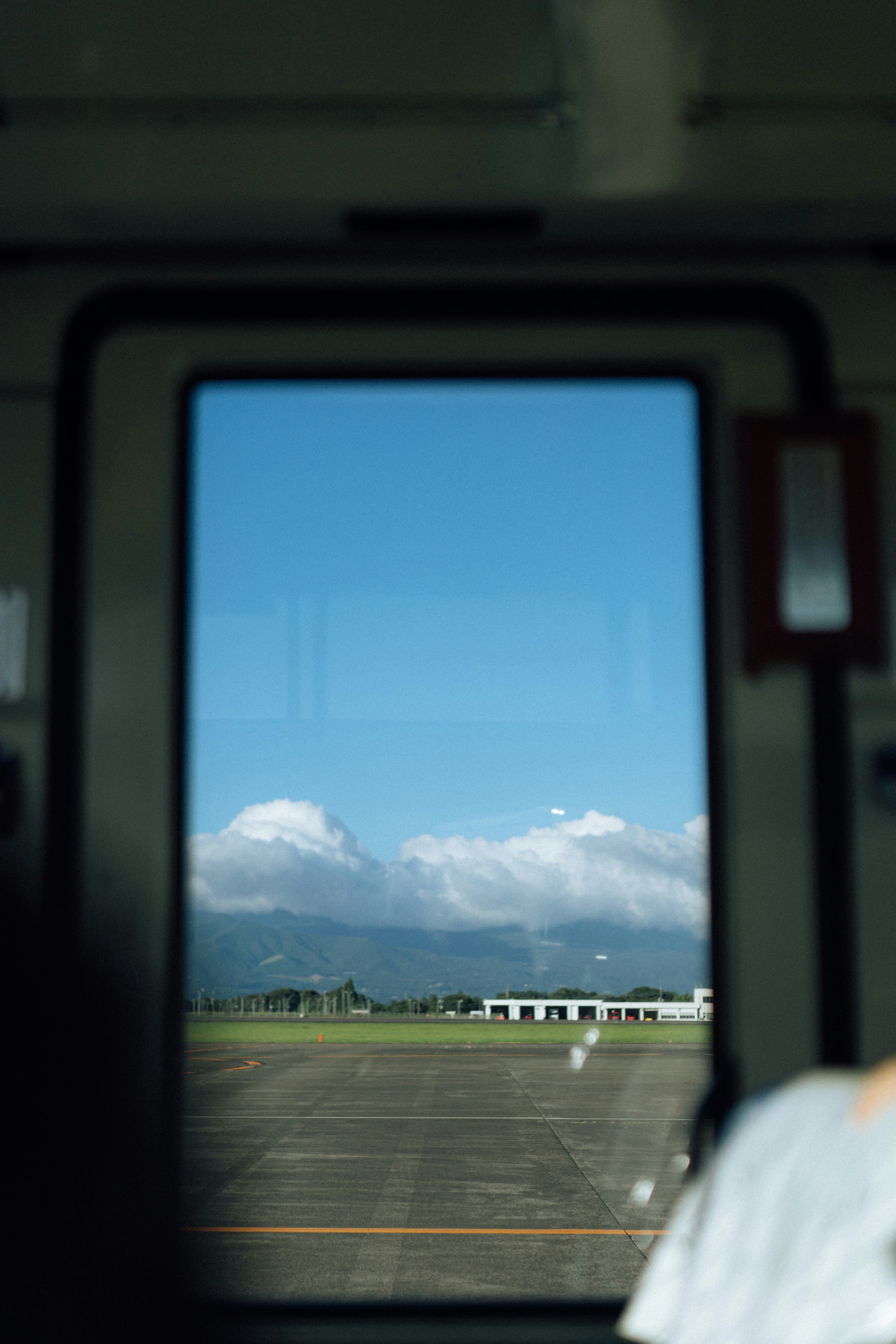 窓越しに見える飛行場の滑走路と山並みの風景