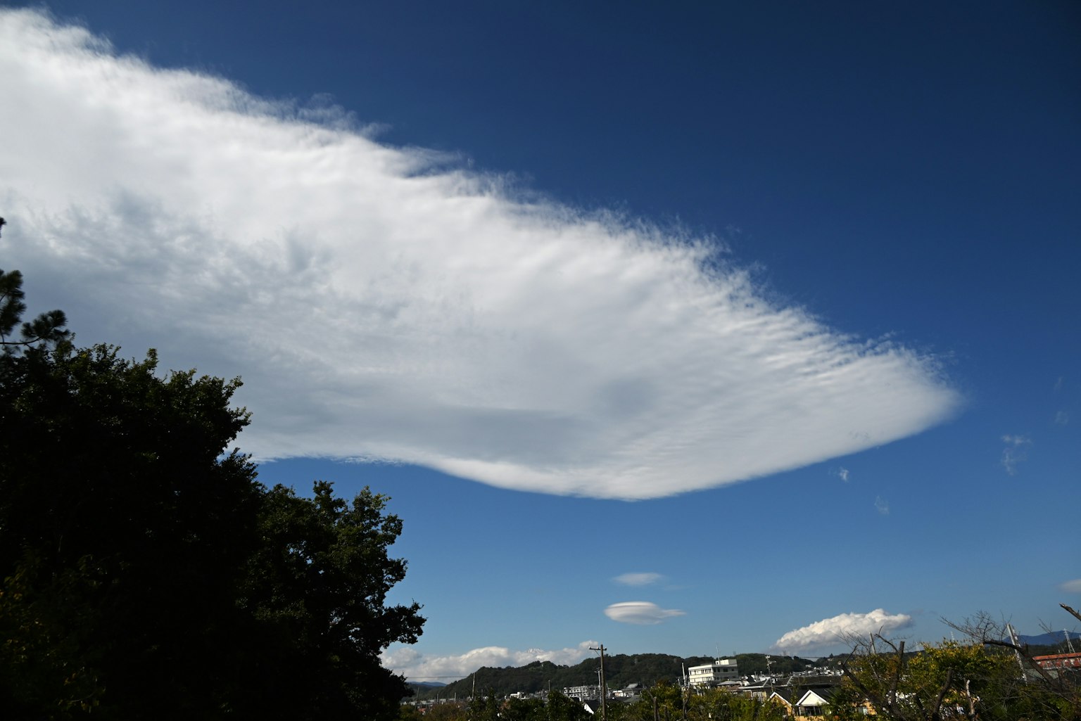 A landscape featuring a vast blue sky with a large white cloud
