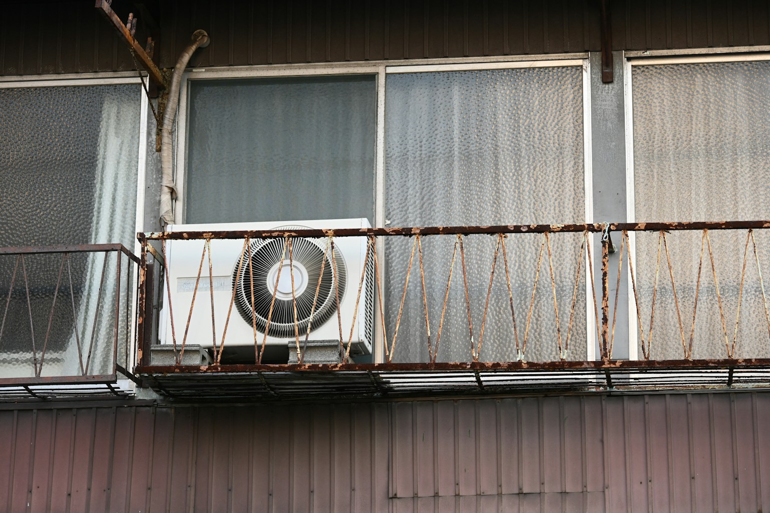 오래된 아파트 발코니에 있는 에어컨과 녹슨 난간