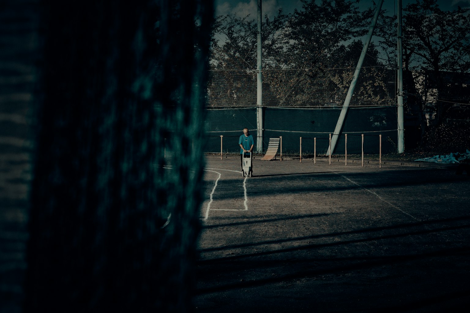 Silhouette of a player standing on a dimly lit tennis court