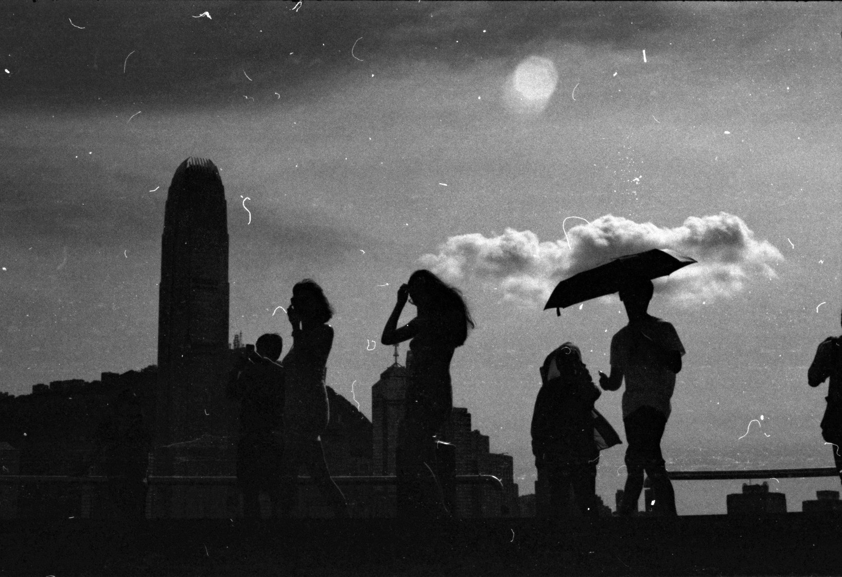 香港の夜景を背景にしたシルエットの人々の散歩風景