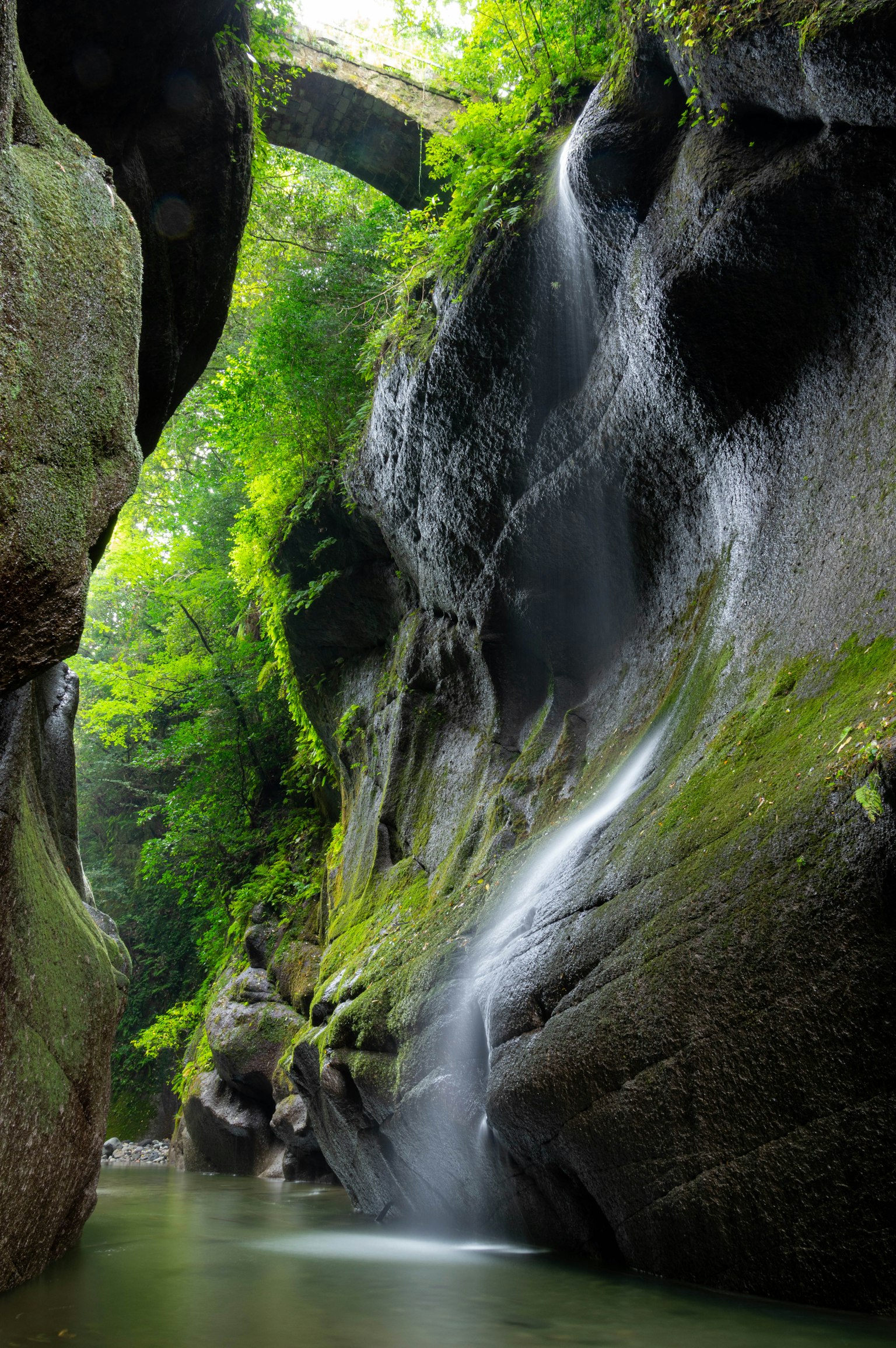 Hermoso paisaje de una cascada en un cañón verde con paredes de piedra