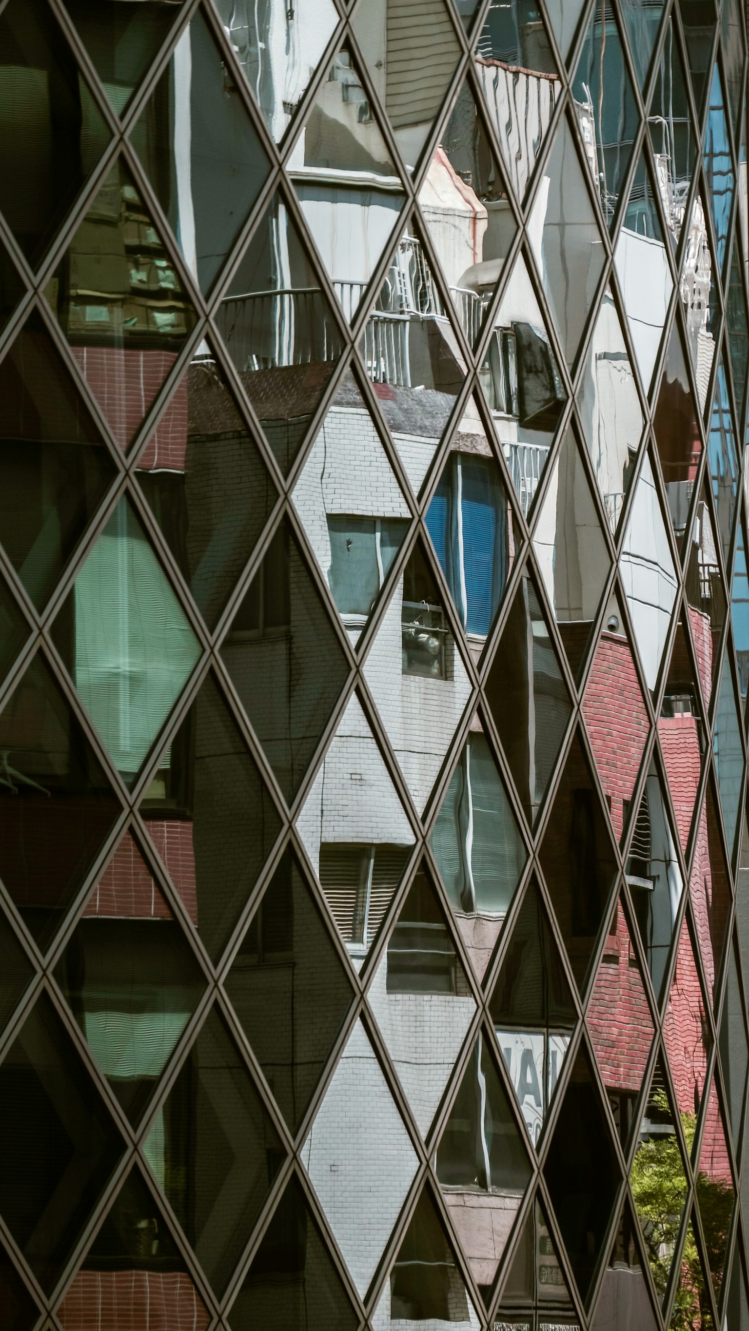 Fenêtres d'un bâtiment moderne se reflétant sur une façade en verre à motif de diamant