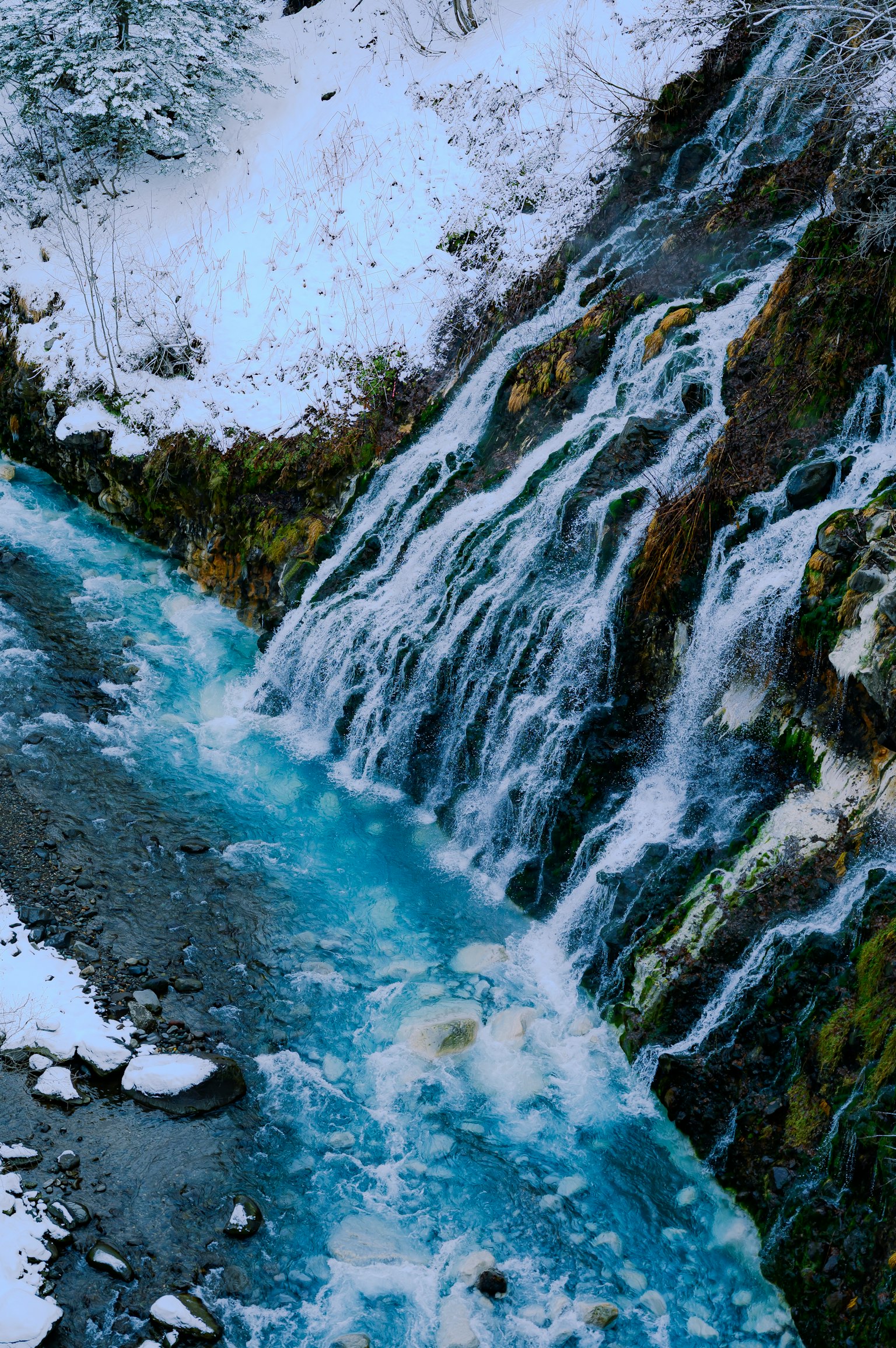 雪に覆われた滝と青い水流の美しい風景
