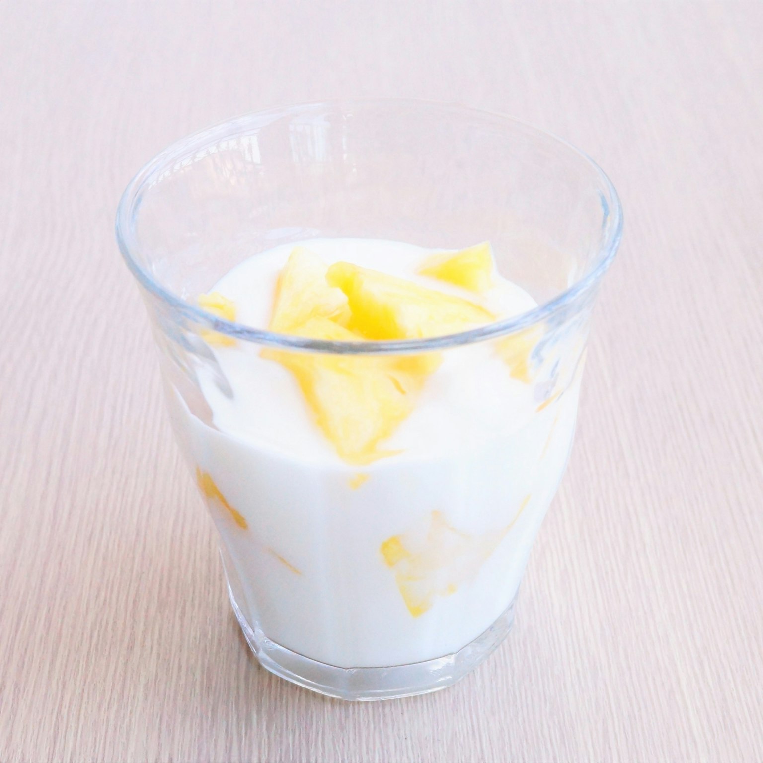 Dessert in a clear glass featuring yogurt and mango pieces