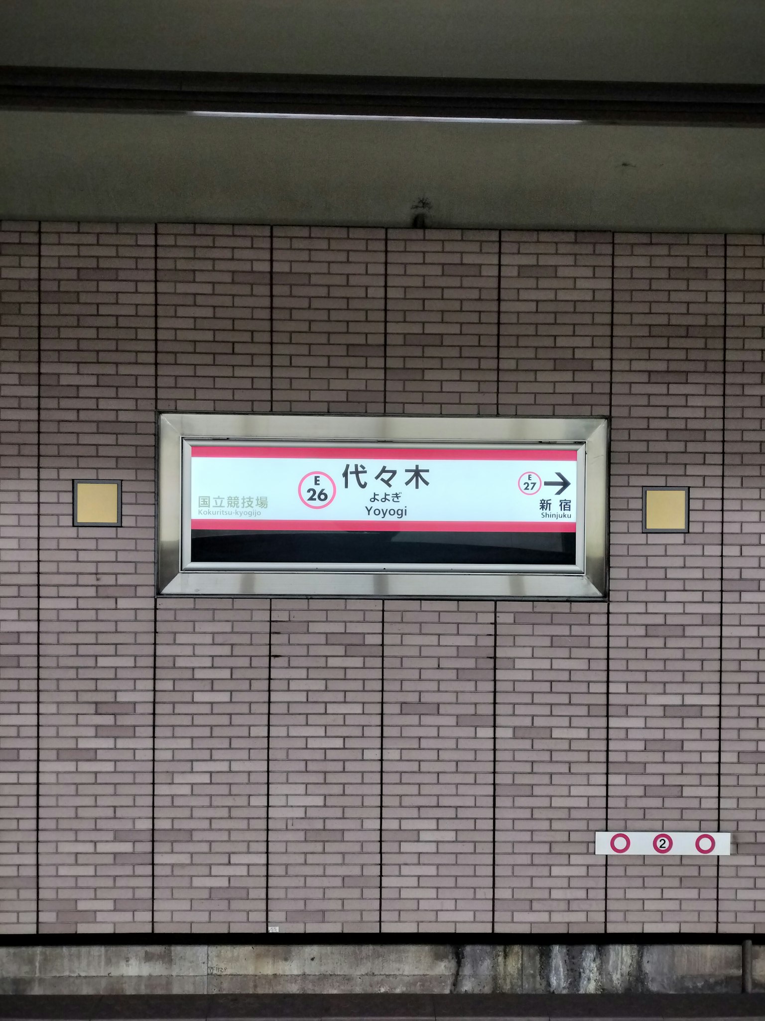 Photo d'un panneau de gare et d'un mur en briques