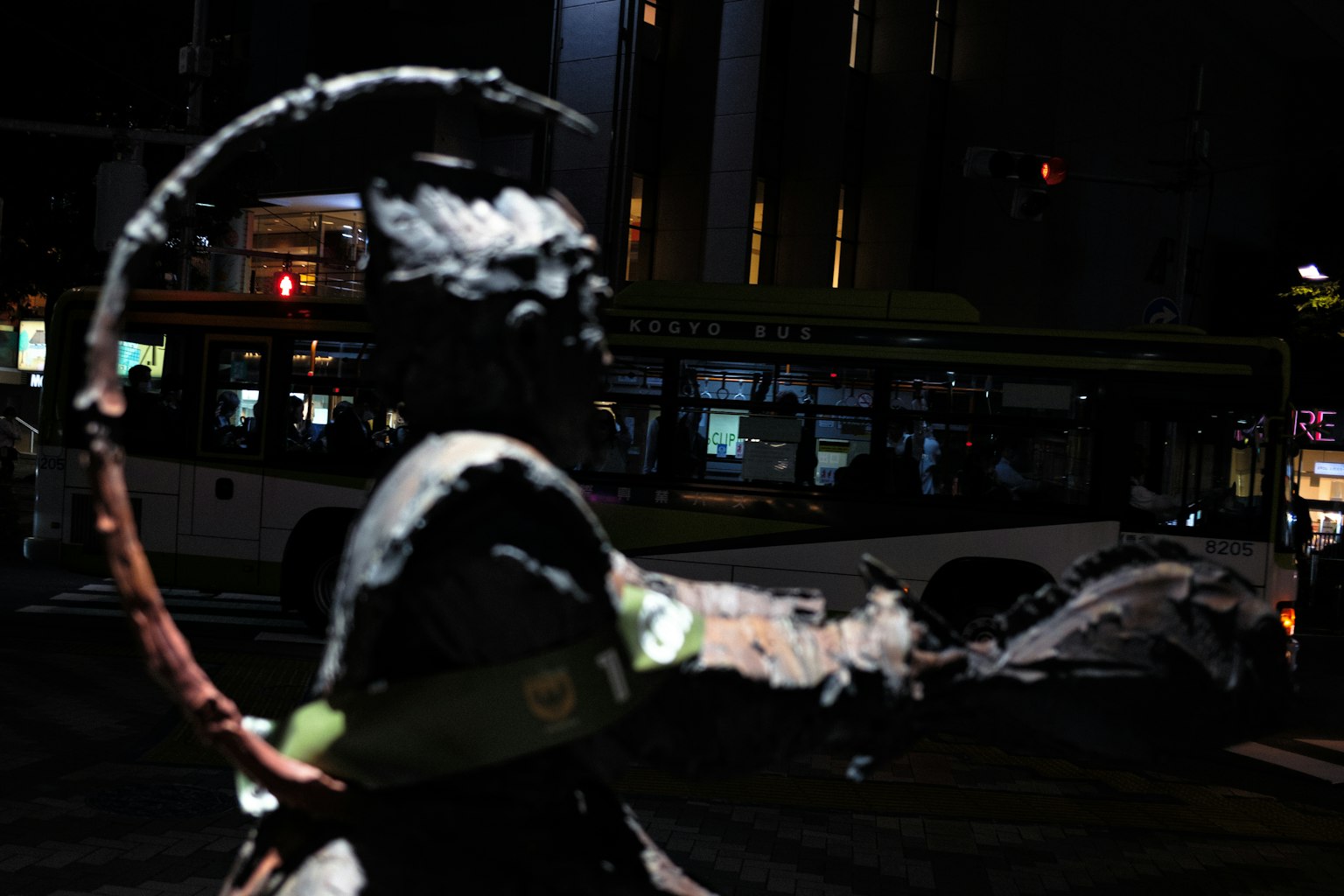 Silueta de una estatua de noche con sombras y luces de la ciudad