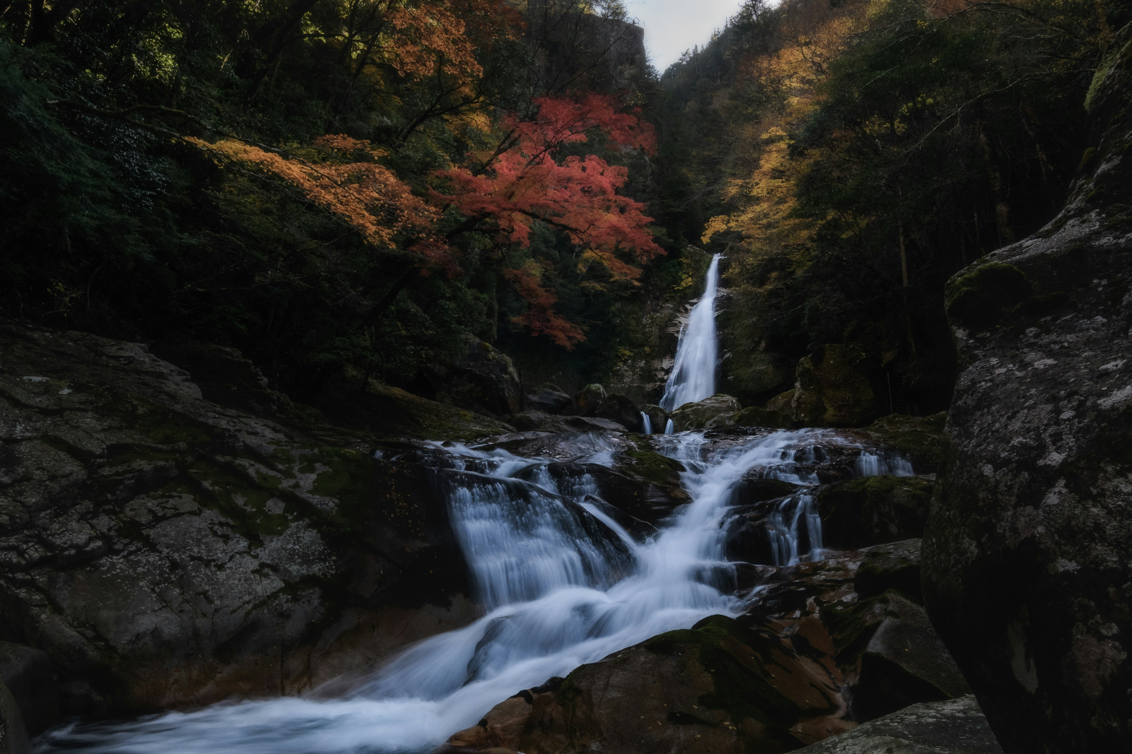 渓流を流れる滝と紅葉の山並み