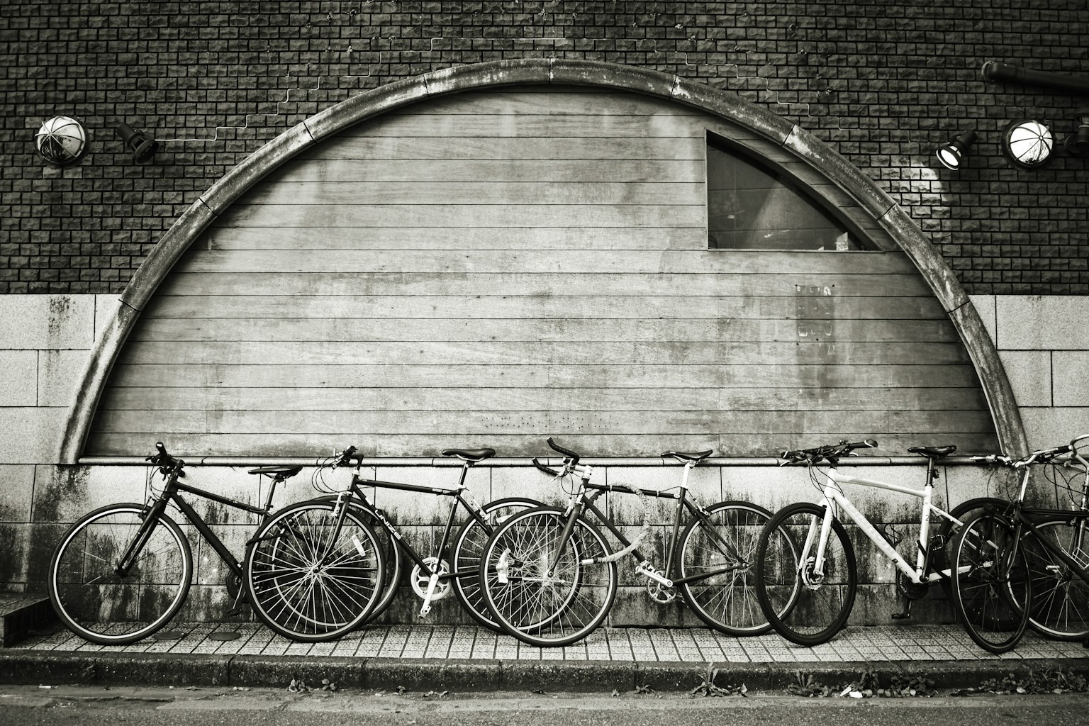 Rangée de vélos contre un mur texturé en noir et blanc