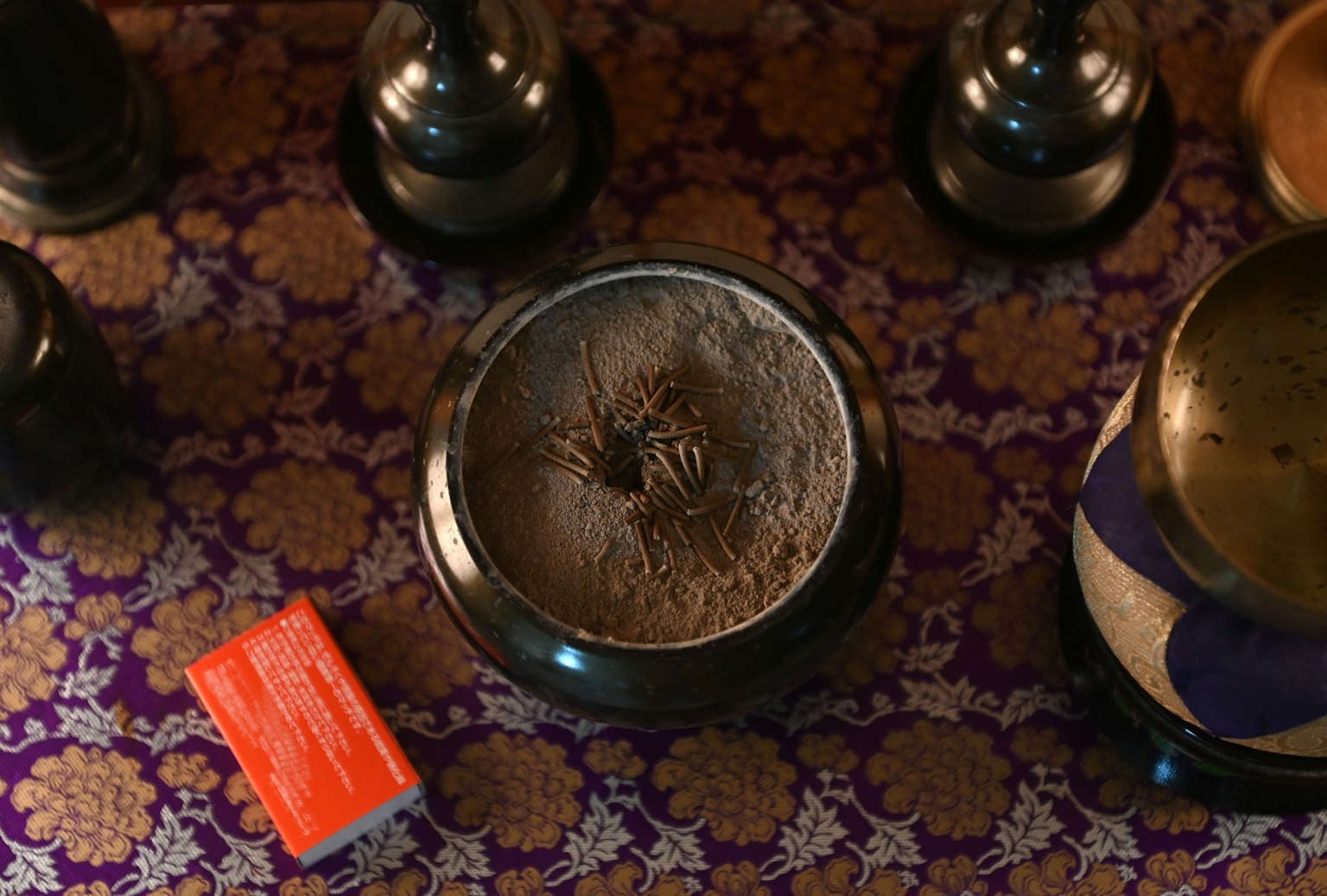 Sự kết hợp của đế hương và hộp đỏ trên vải tím có họa tiết