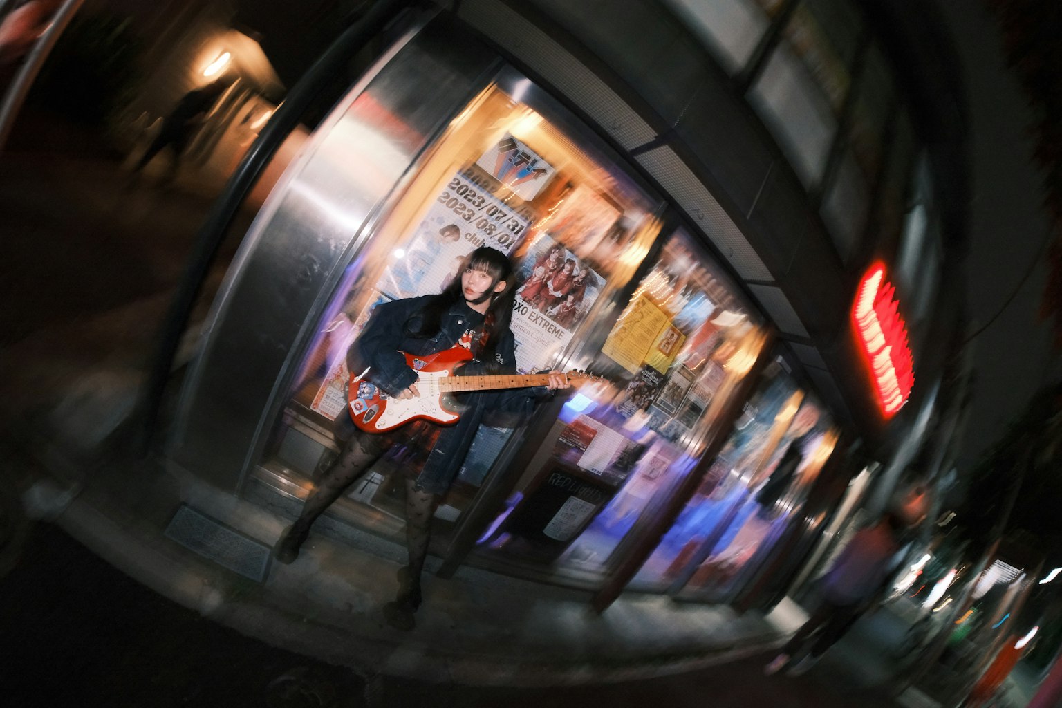 夜晚街角的音乐家在明亮的商店前拿着吉他