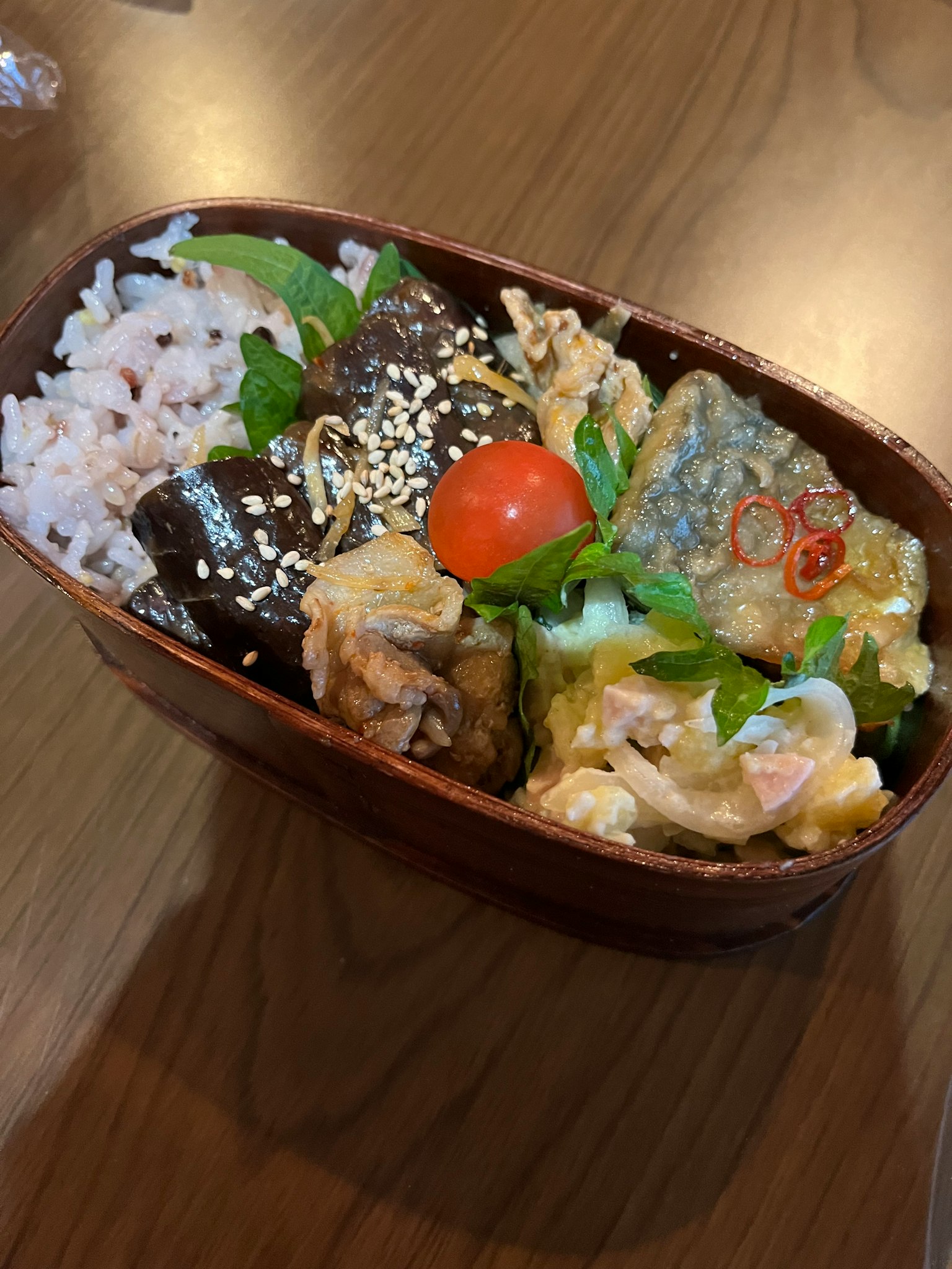 Scatola bento colorata piena di vari ingredienti e riso rosso