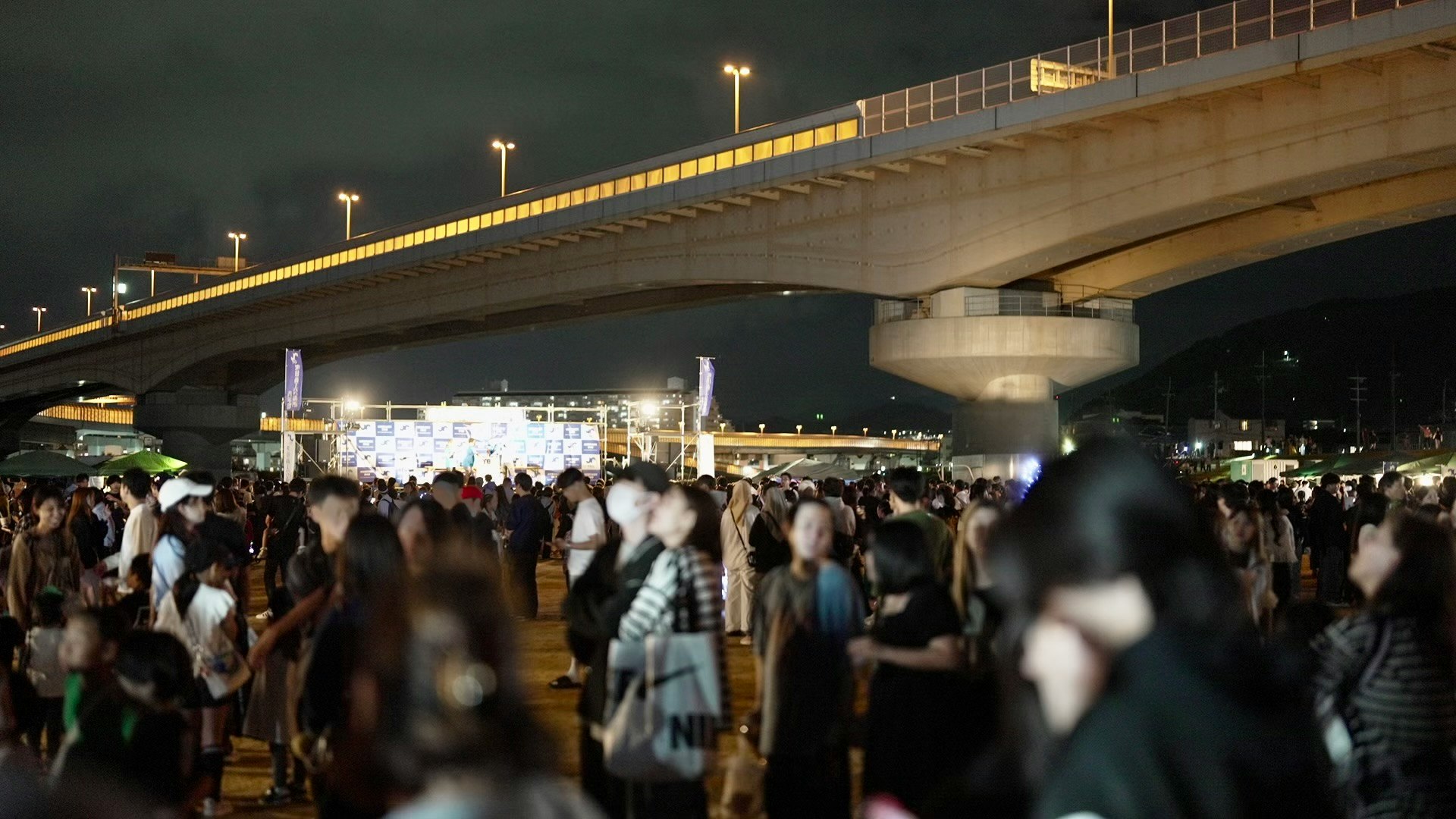 高架下の夜に集まる人々のにぎやかな祭りの行列