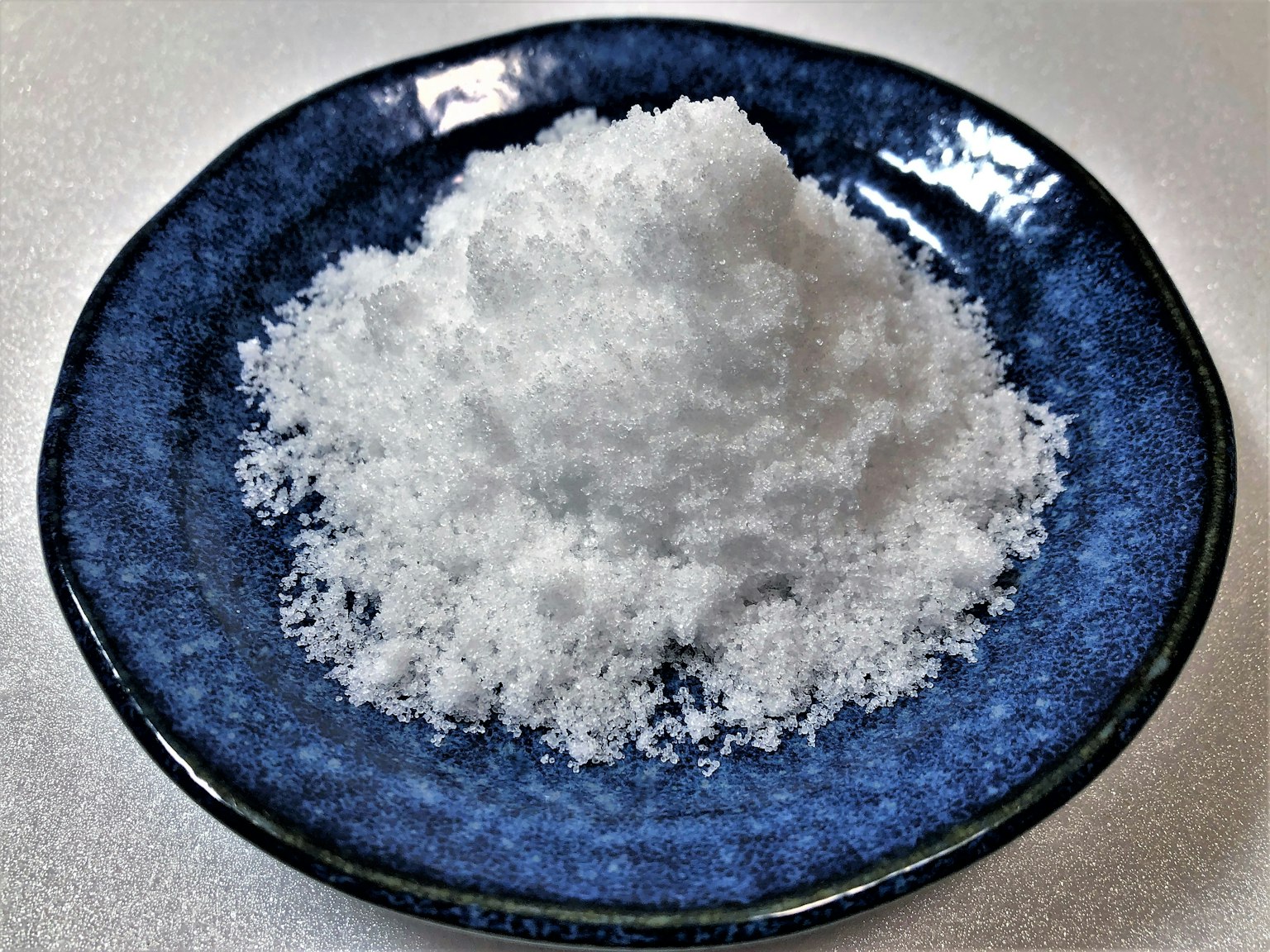 Một đống muối trắng trên đĩa màu xanh