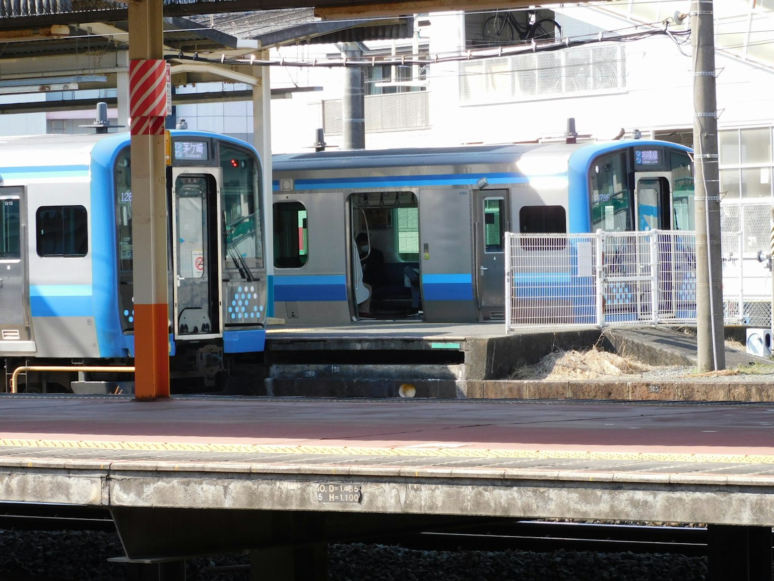 Un train avec des rayures bleues est arrêté à une station