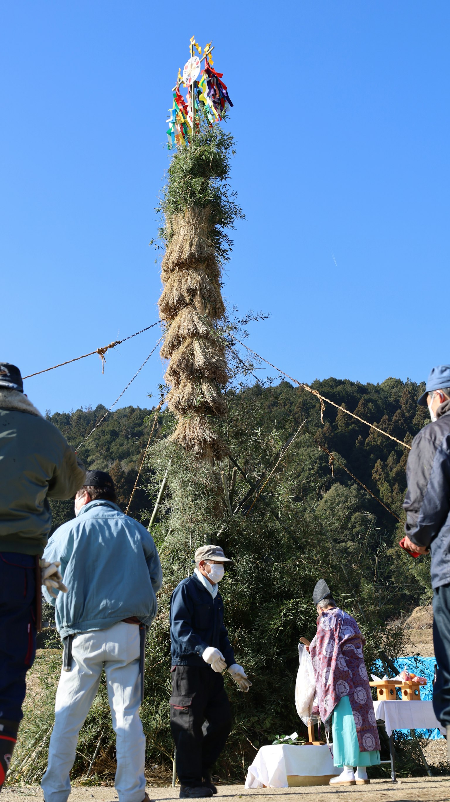 Una estructura alta de hierba bajo un cielo azul con personas reunidas