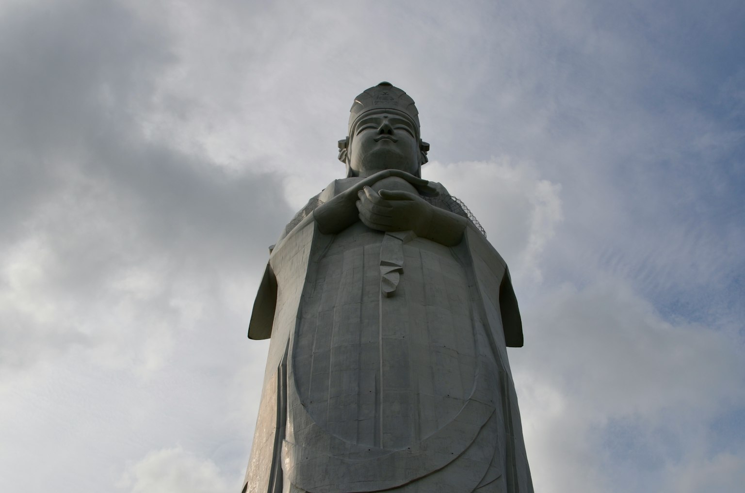 Estatua blanca alta vista desde abajo con las manos juntas frente a ella