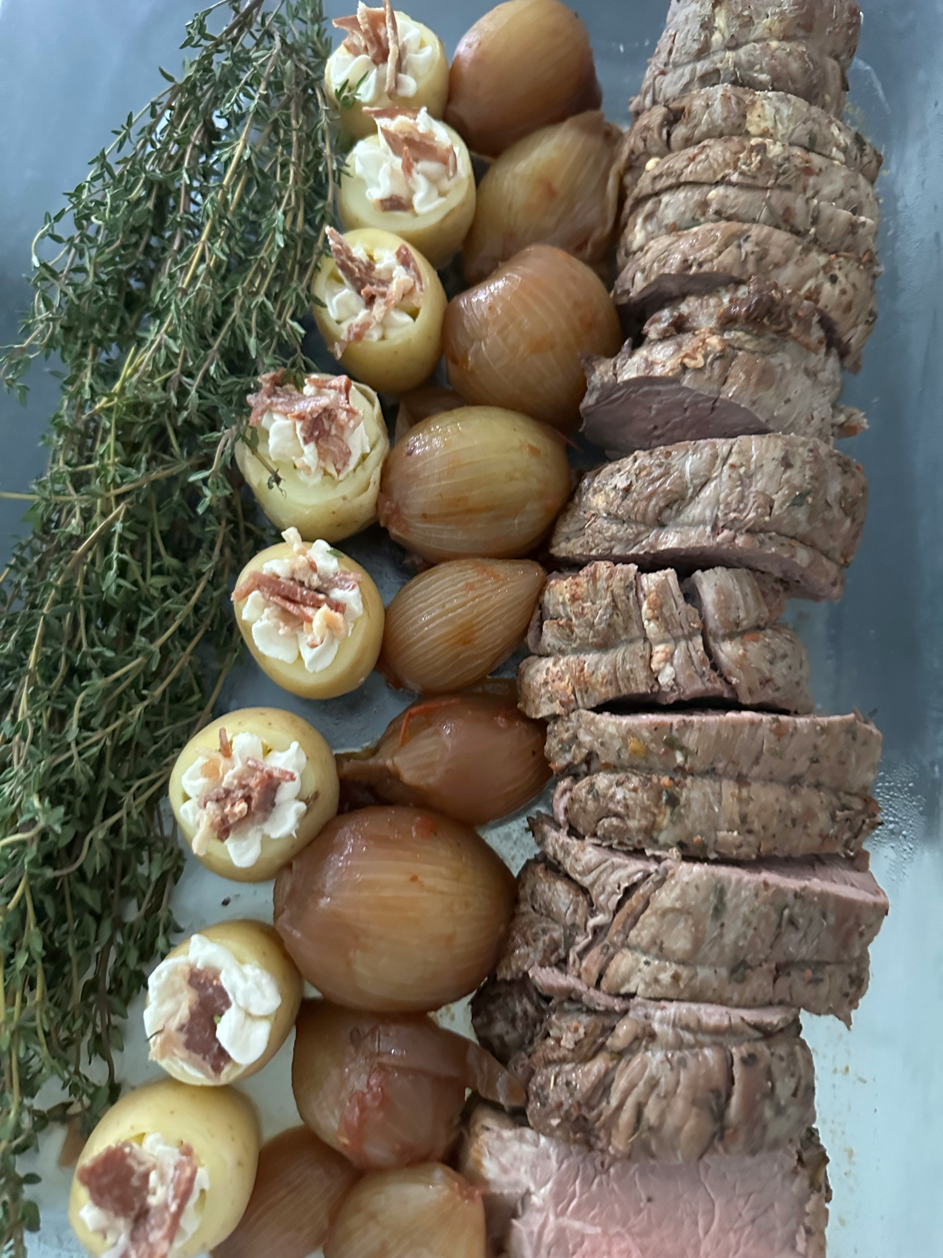 玉ねぎの輪切りとハーブ、肉の塊が並ぶ食材の盛り合わせ