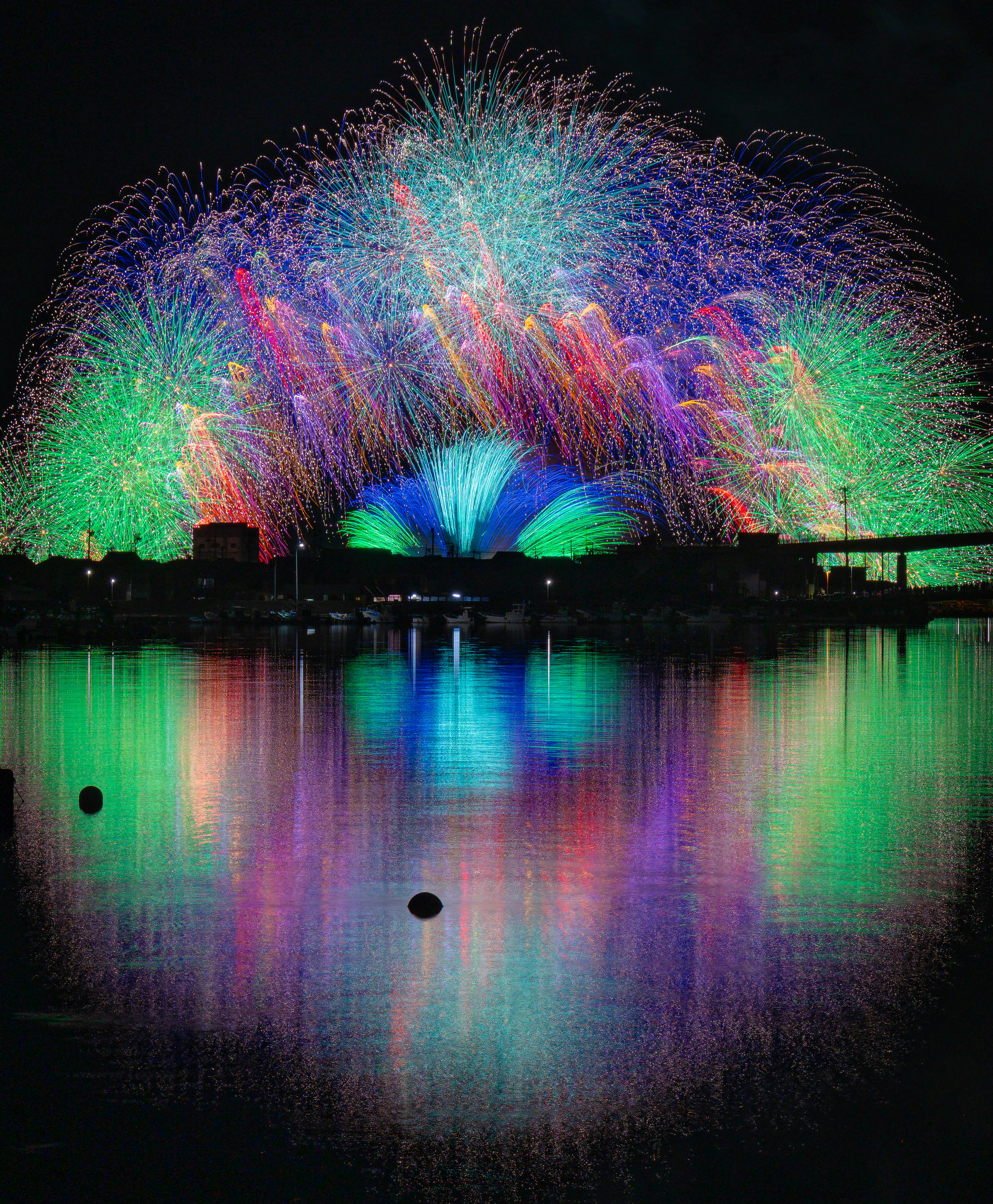水面に映るカラフルな噴水と光の花火のような演出の夜景