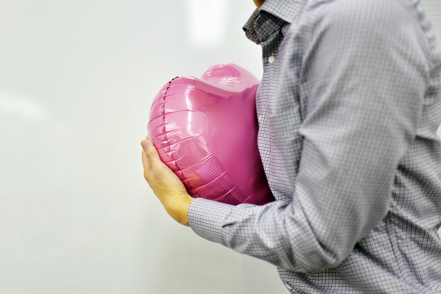 Seorang pria memegang balon berbentuk hati berwarna pink