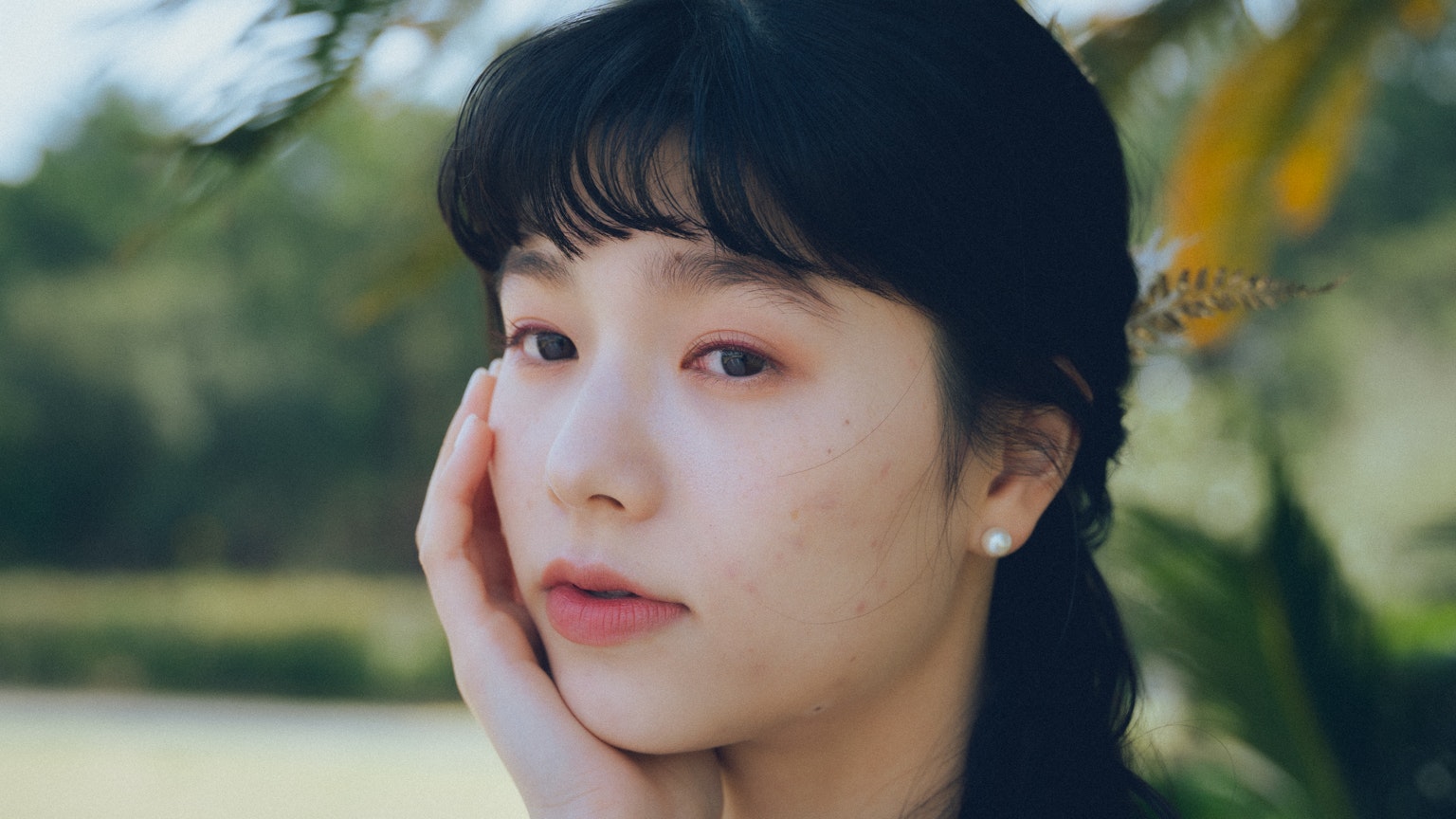 ภาพถ่ายหญิงสาวกลางแจ้งมีสีหน้าคิดอยู่แตะที่ใบหน้า