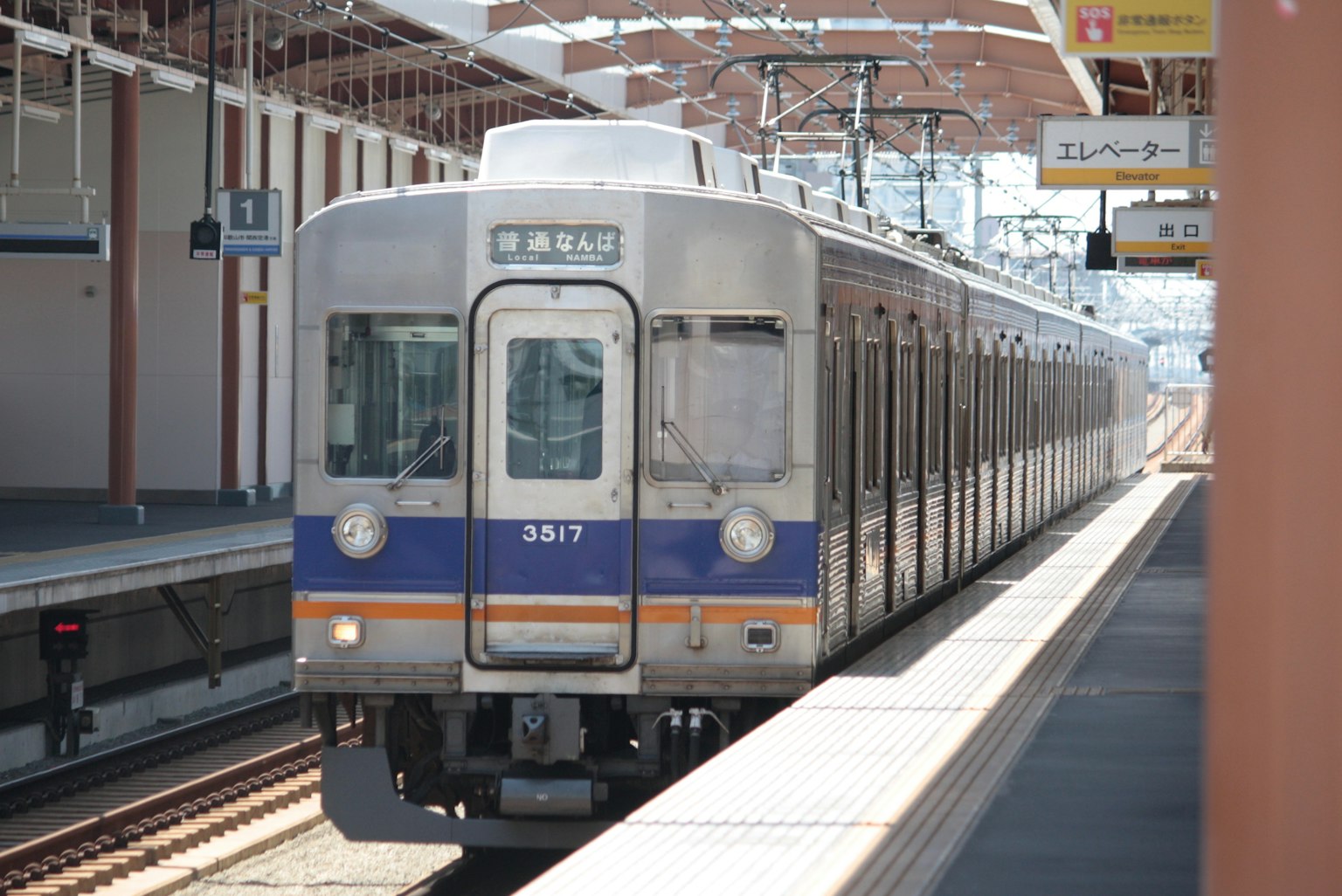 Train arrivant à une gare avec des voies et un quai visibles