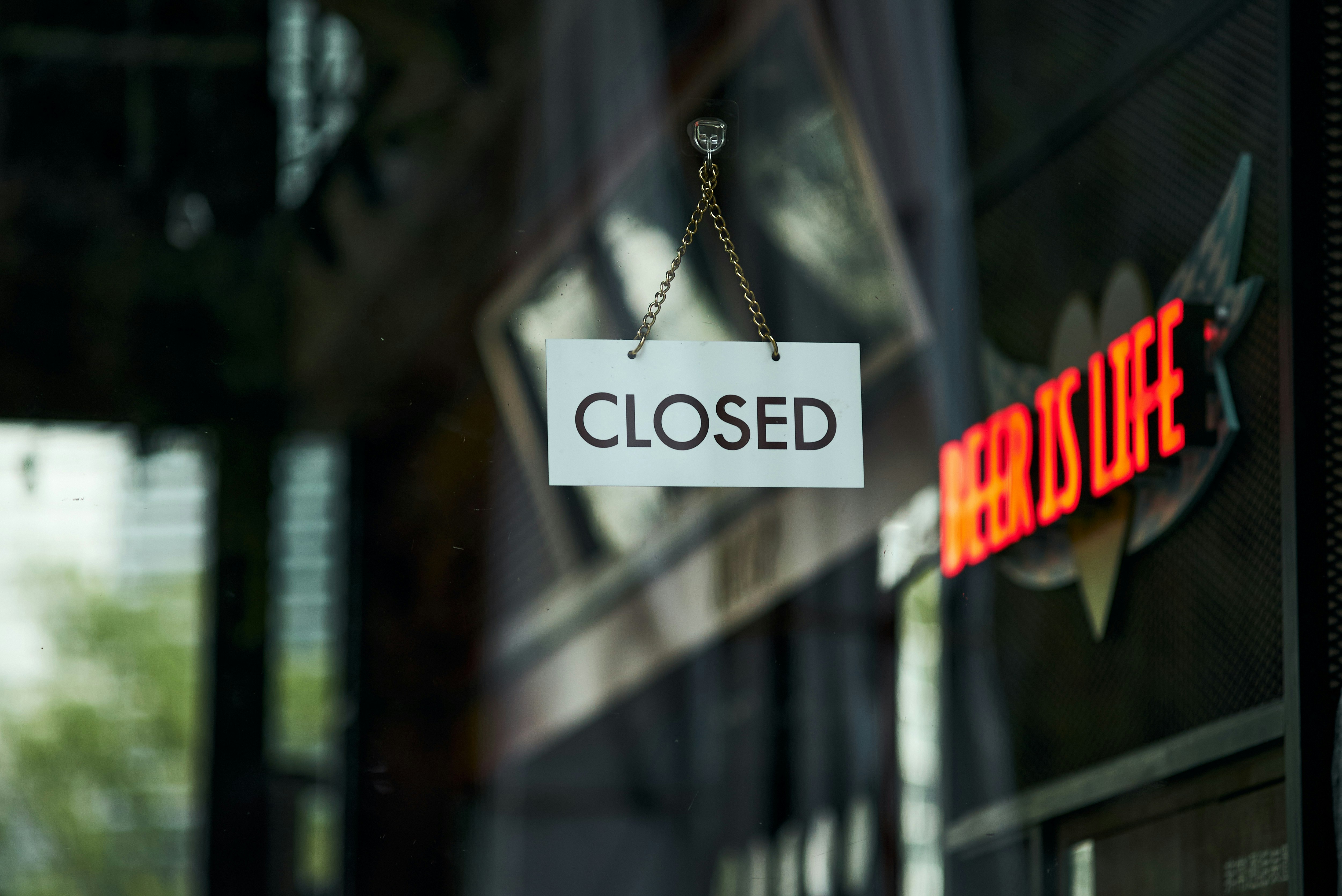 「CLOSED」看板が下がる店のガラス扉の前景