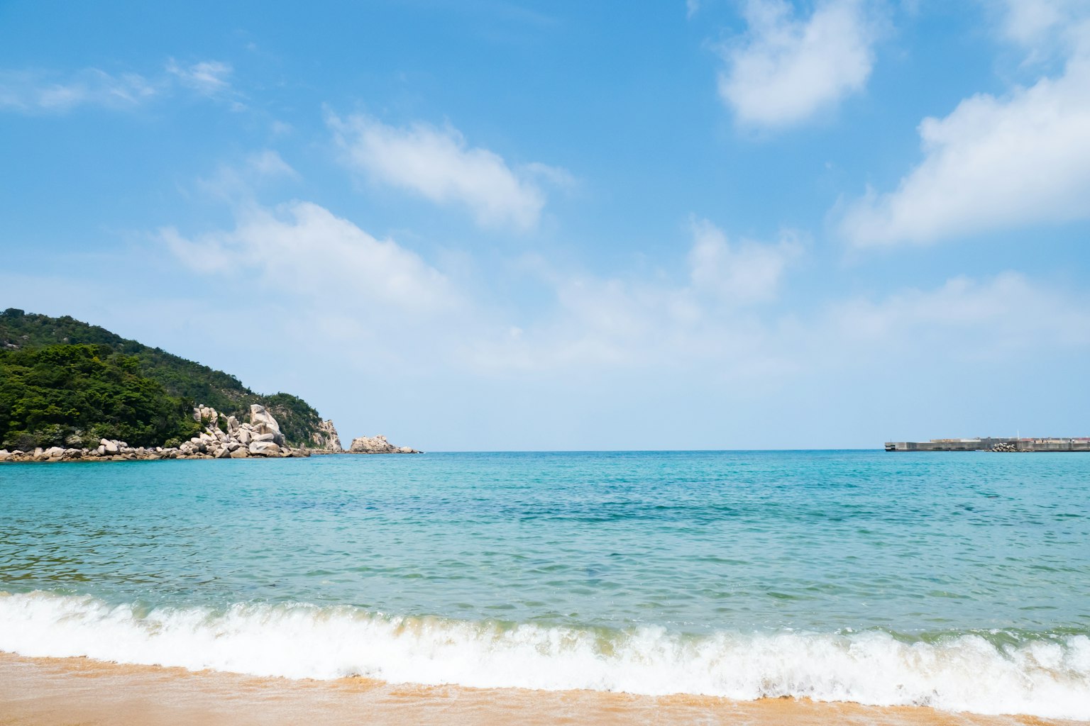 Vue panoramique d'une mer bleue et d'une plage de sable avec des nuages dans le ciel